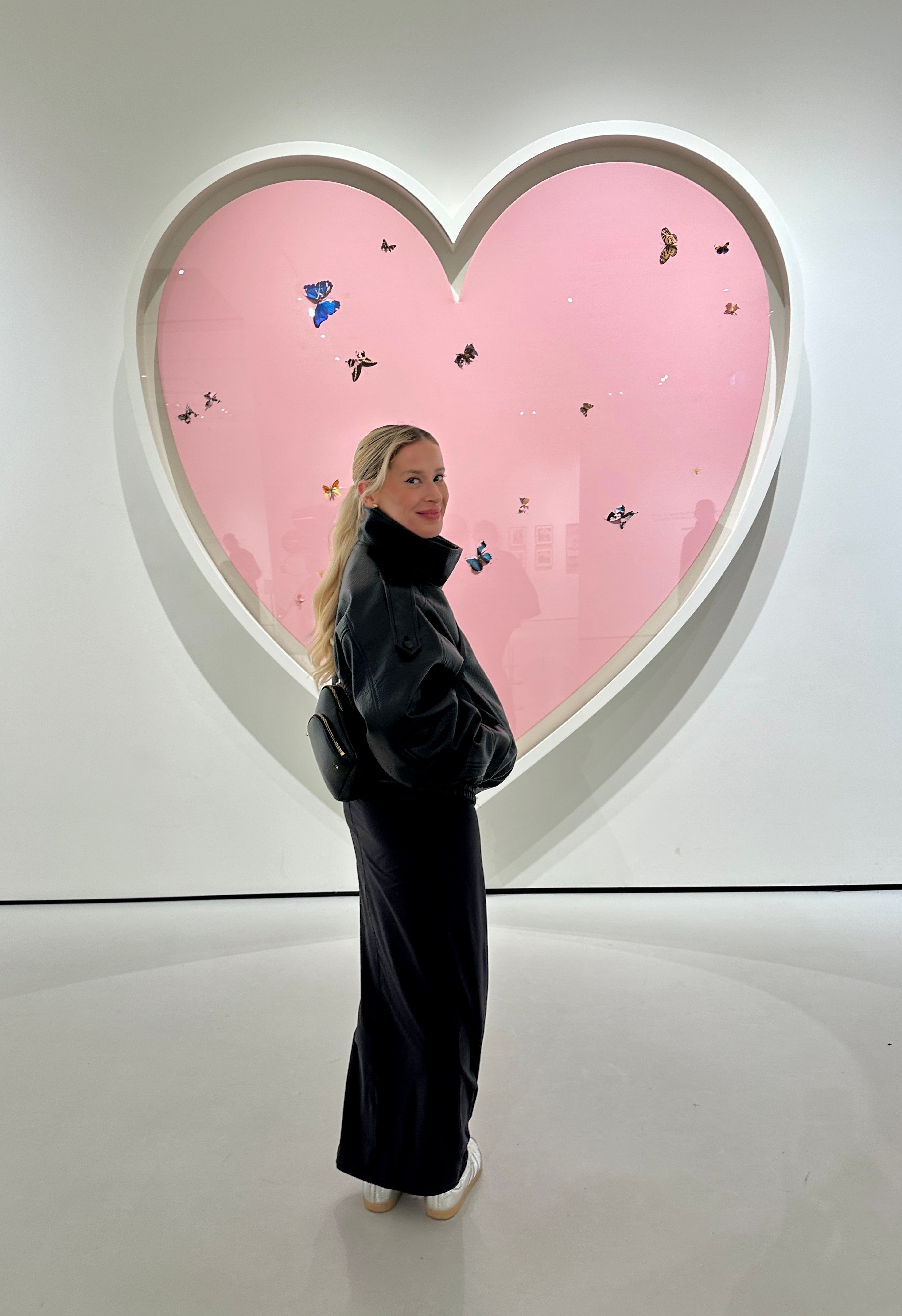 Molly Normanding Next to an Art Piece resembling a Pink Heart.