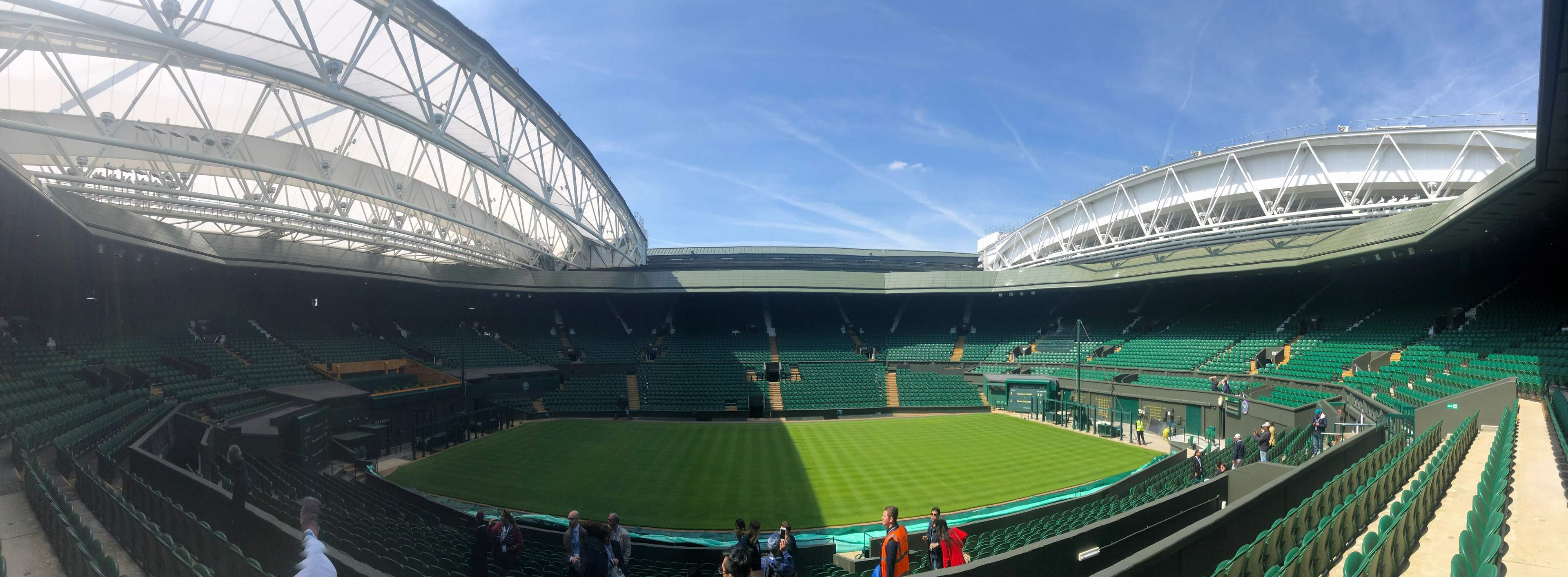 An empty Centre Court at Wimbledon with freshly striped grass under the open roof