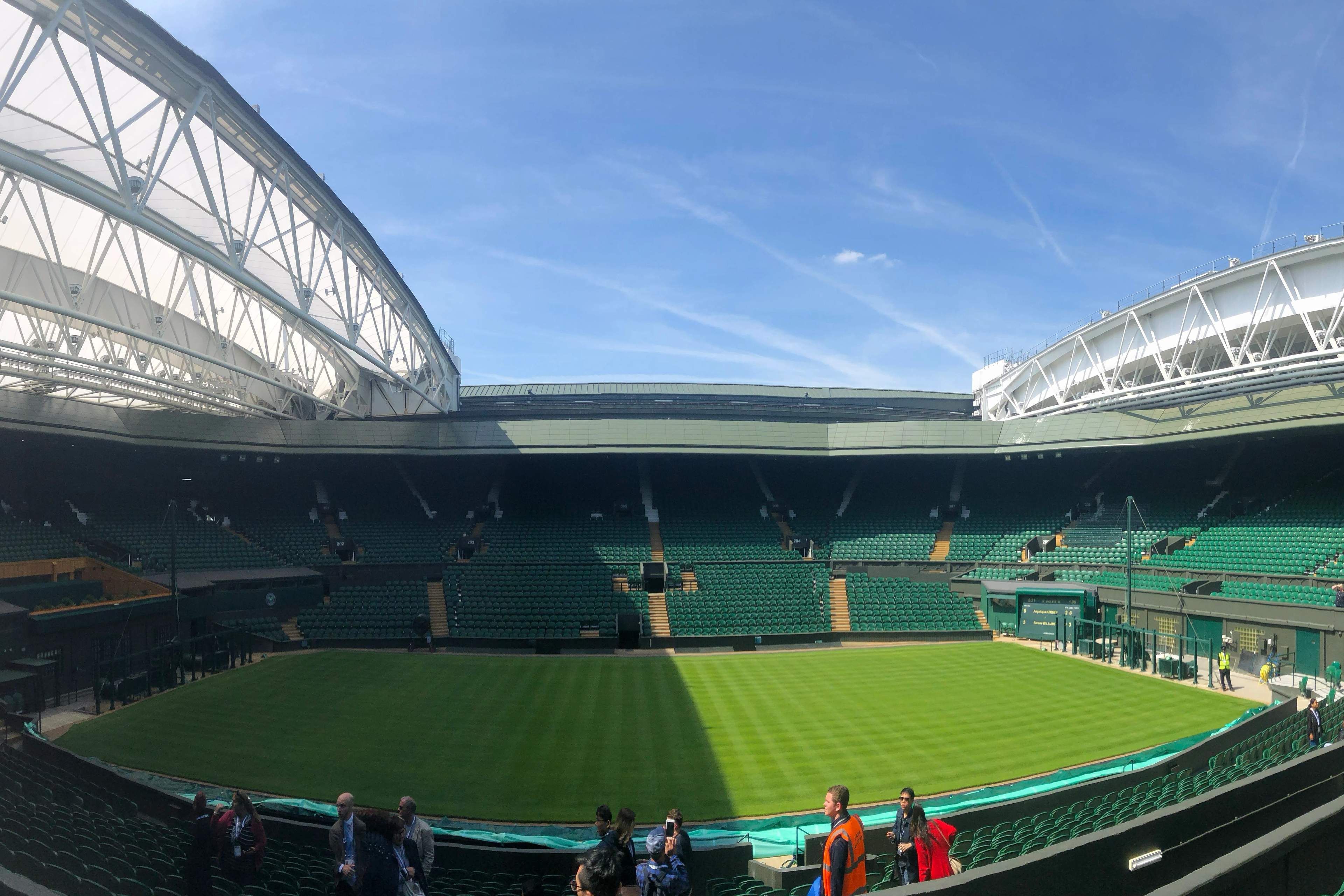 An empty Centre Court at Wimbledon with freshly striped grass under the open roof