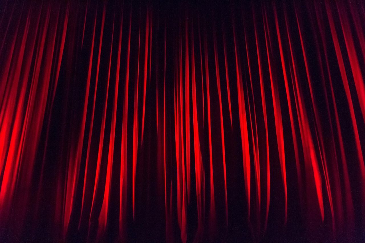 Theatre stage with red curtain, representing the UK premiere of The Devil Wears Prada musical