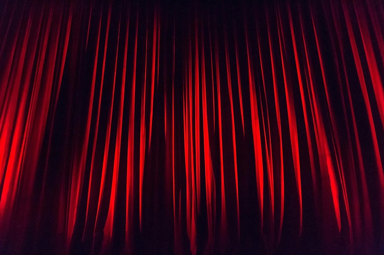 Theatre stage with red curtain, representing the UK premiere of The Devil Wears Prada musical