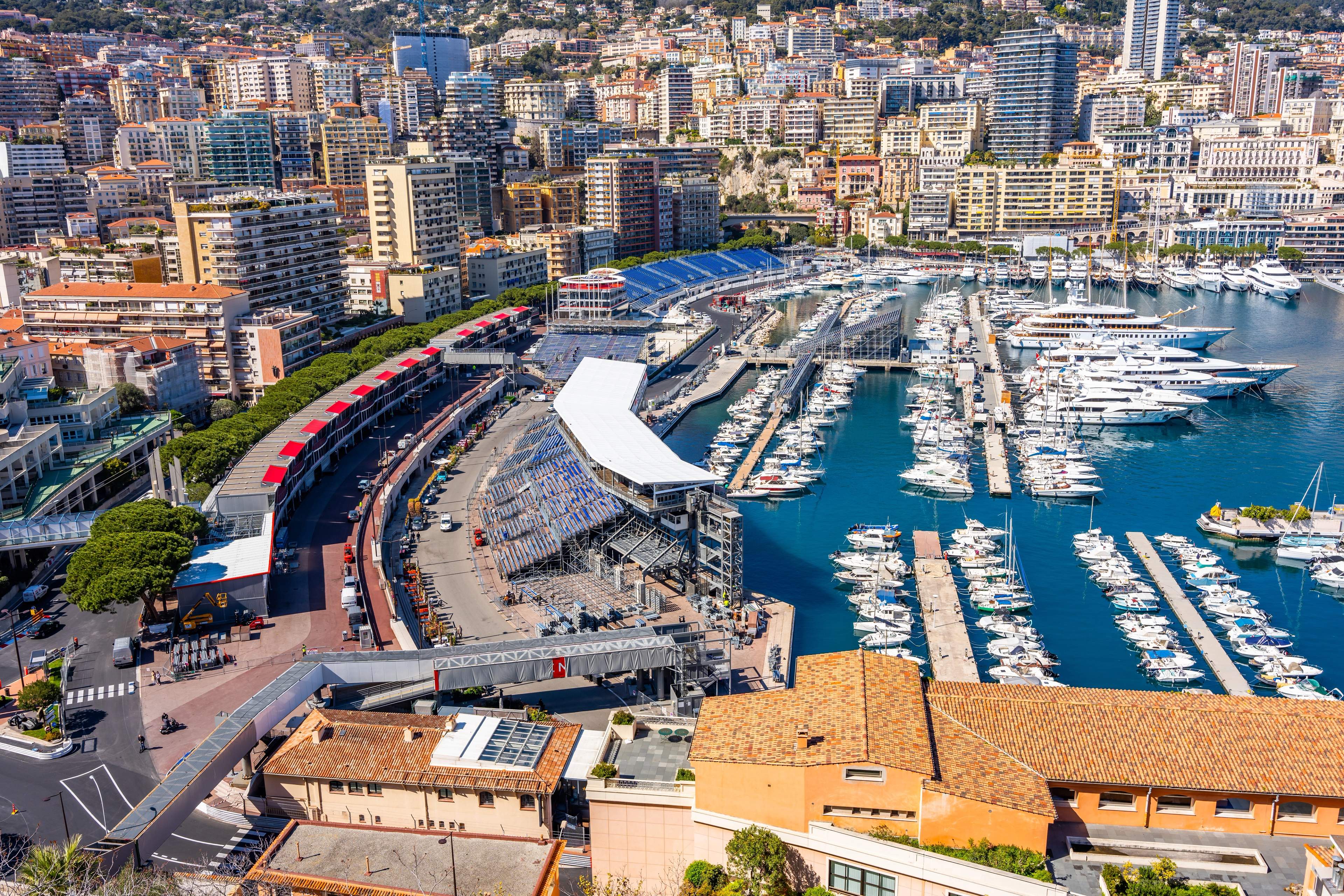 Monaco circuit with F1 cars racing through tight corners, grandstands visible along the famous street track.