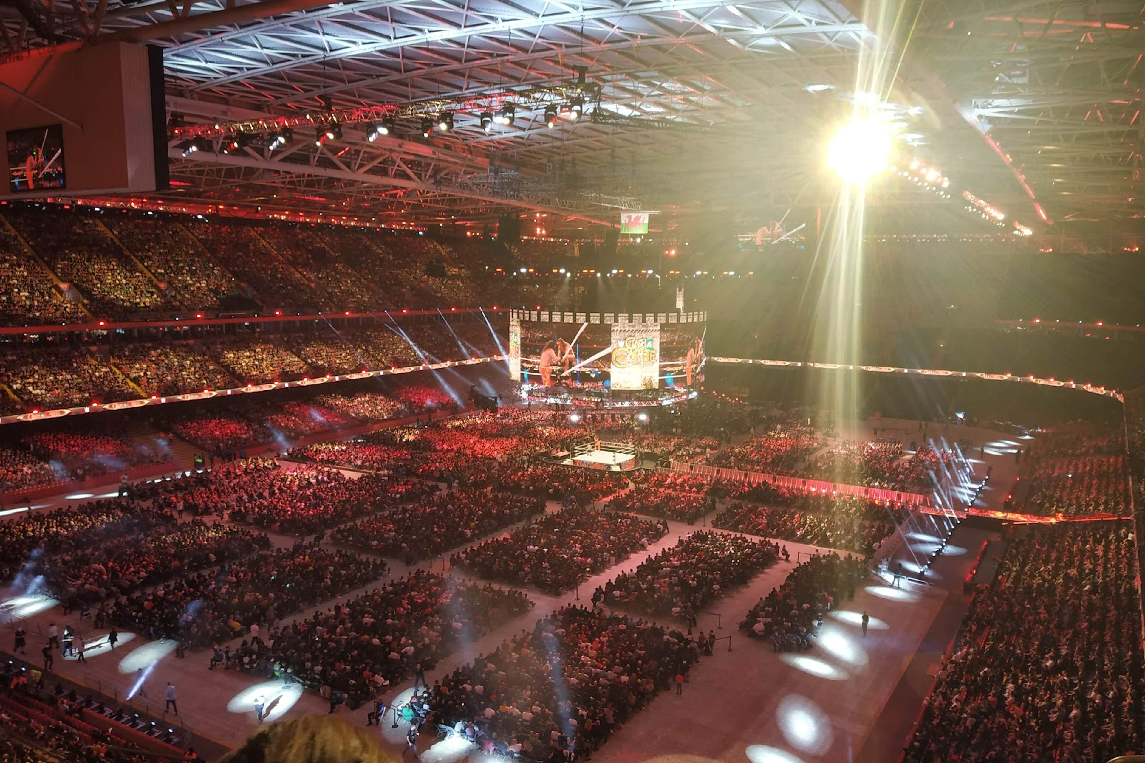 The Principality Stadium under its closed roof, the full bowl lit for an evening show with the floor laid out below