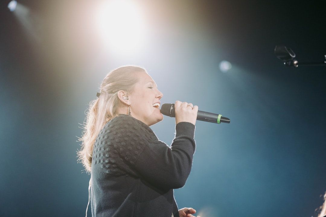 Singer performing live on stage with microphone under coloured lights