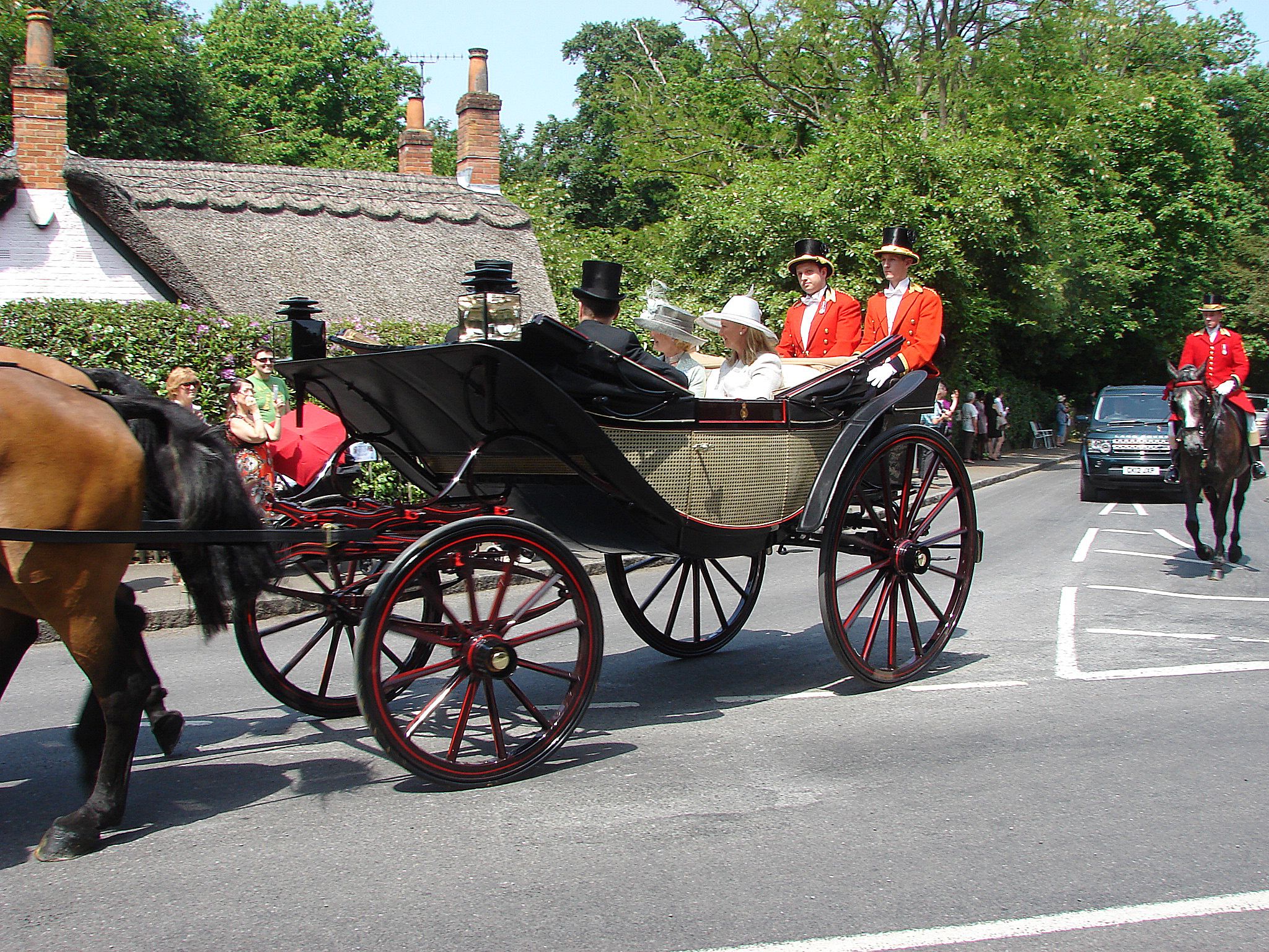 The royal carriage procession travelling to Royal Ascot, with a horse-drawn landau and red-liveried postilions
