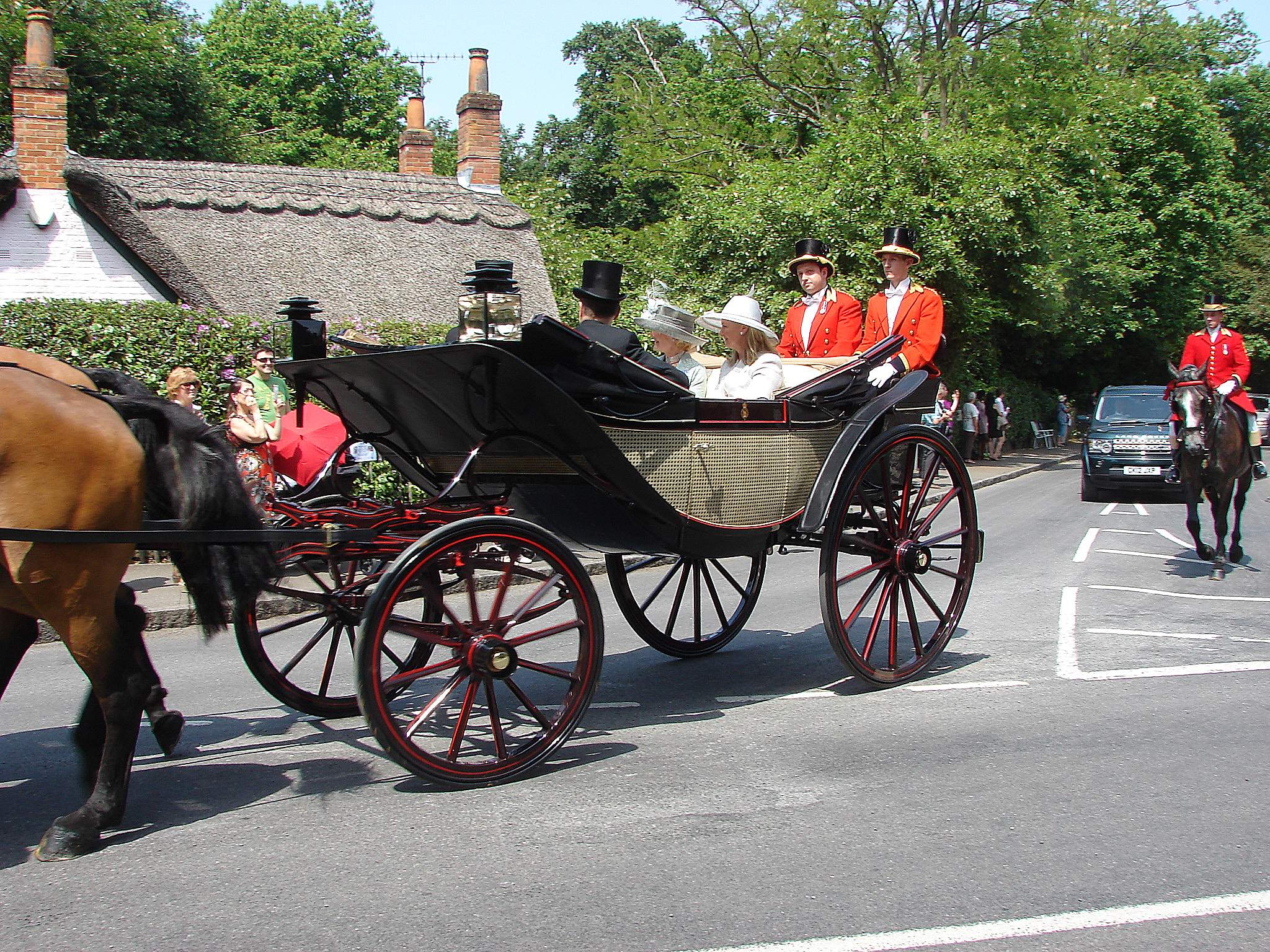The royal carriage procession travelling to Royal Ascot, with a horse-drawn landau and red-liveried postilions