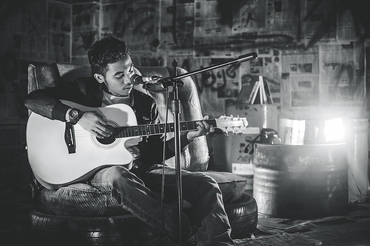 Acoustic guitar player in black and white, evoking the singer-songwriter tradition