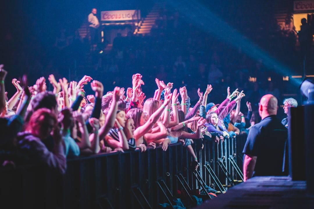Performers on a brightly lit arena stage in front of a large audience