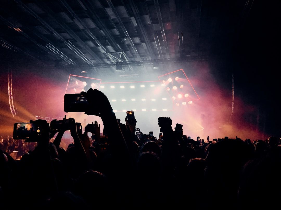 Concert crowd surrounding a stage with dramatic lighting