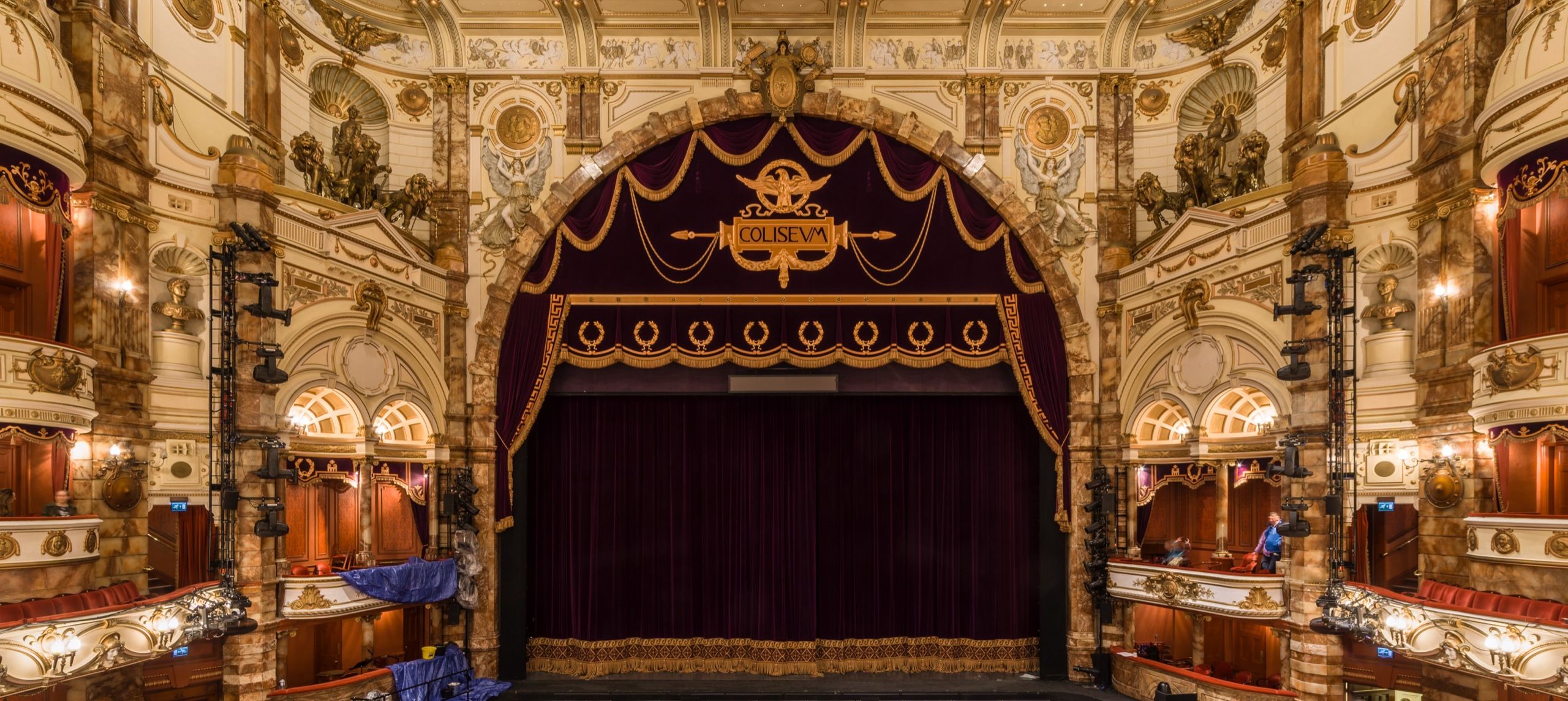 The London Coliseum auditorium from the stalls: house curtain, boxes and gilded tiers
