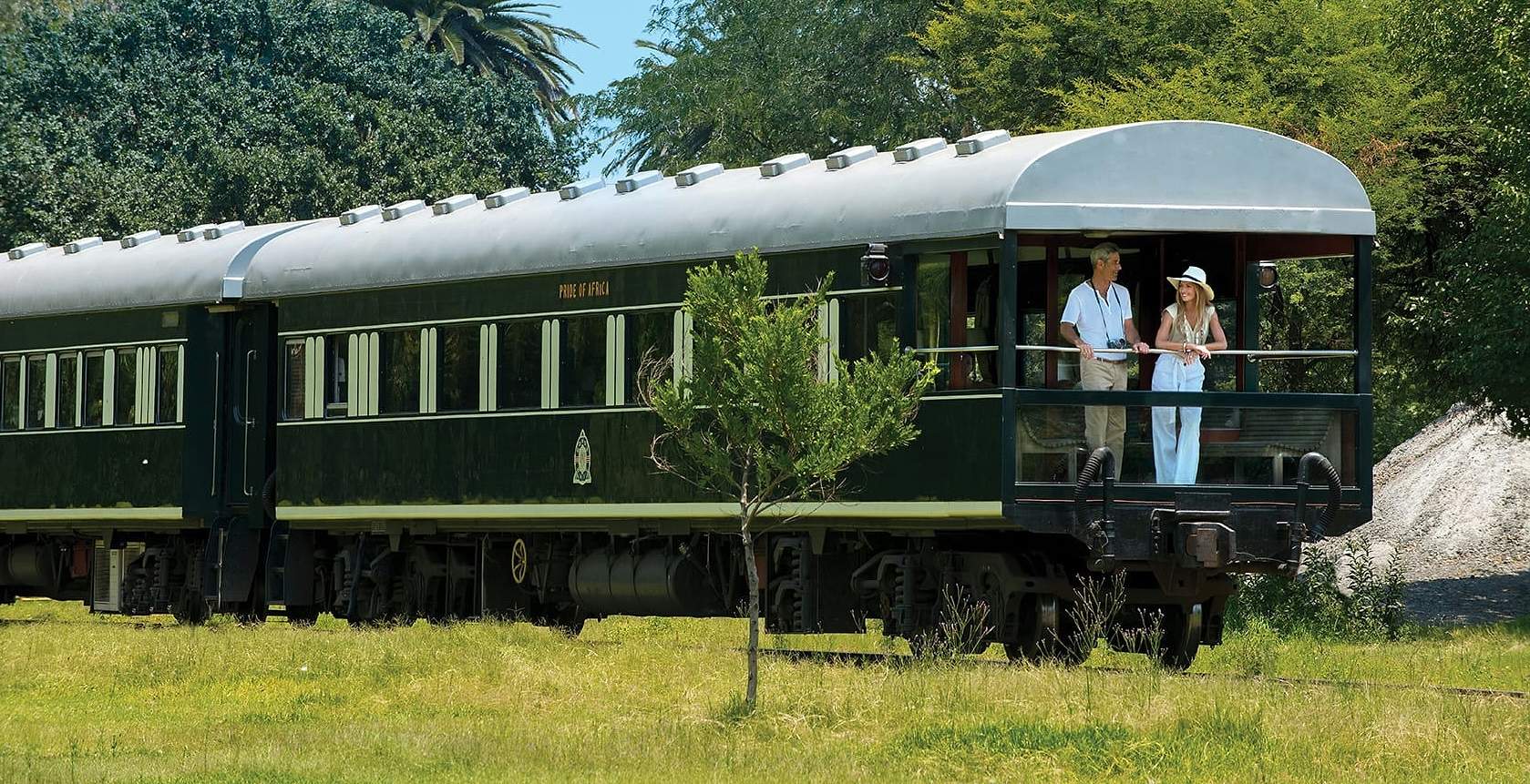 Guests on the open balcony of a Rovos Rail observation car passing through southern African bushveld