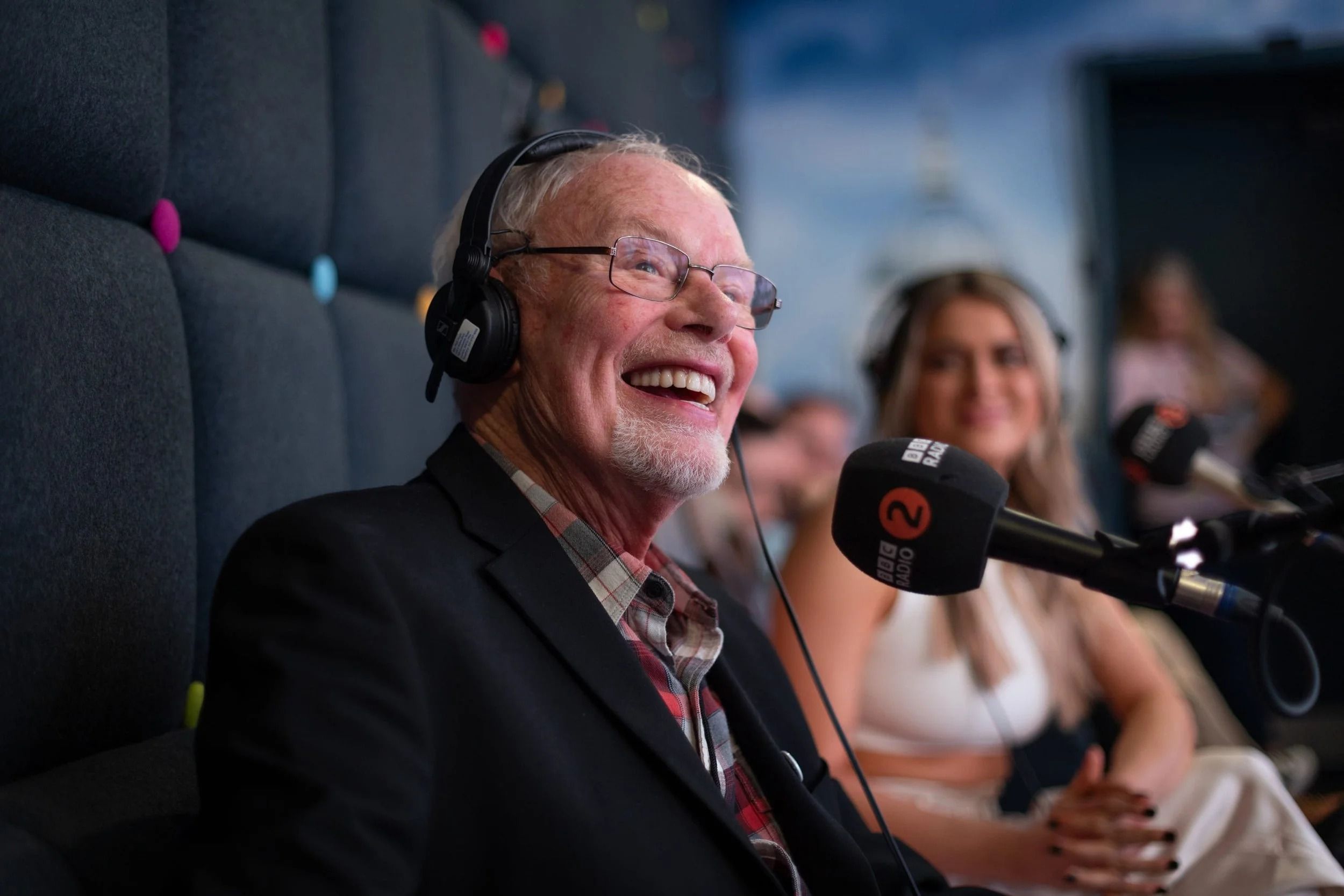 Bob Harris laughing at a BBC Radio 2 microphone, with headphones on