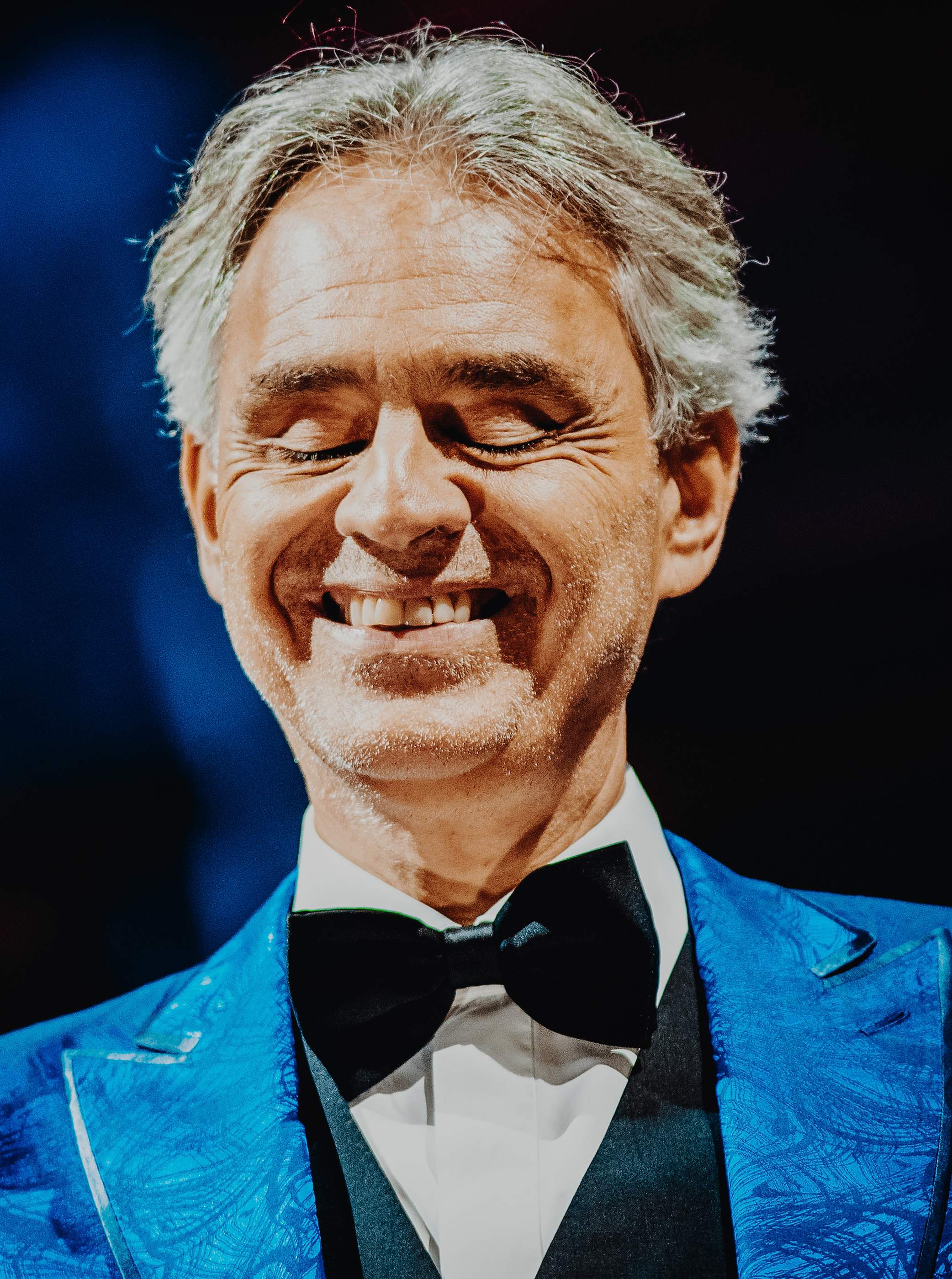 Andrea Bocelli smiling in a blue jacket