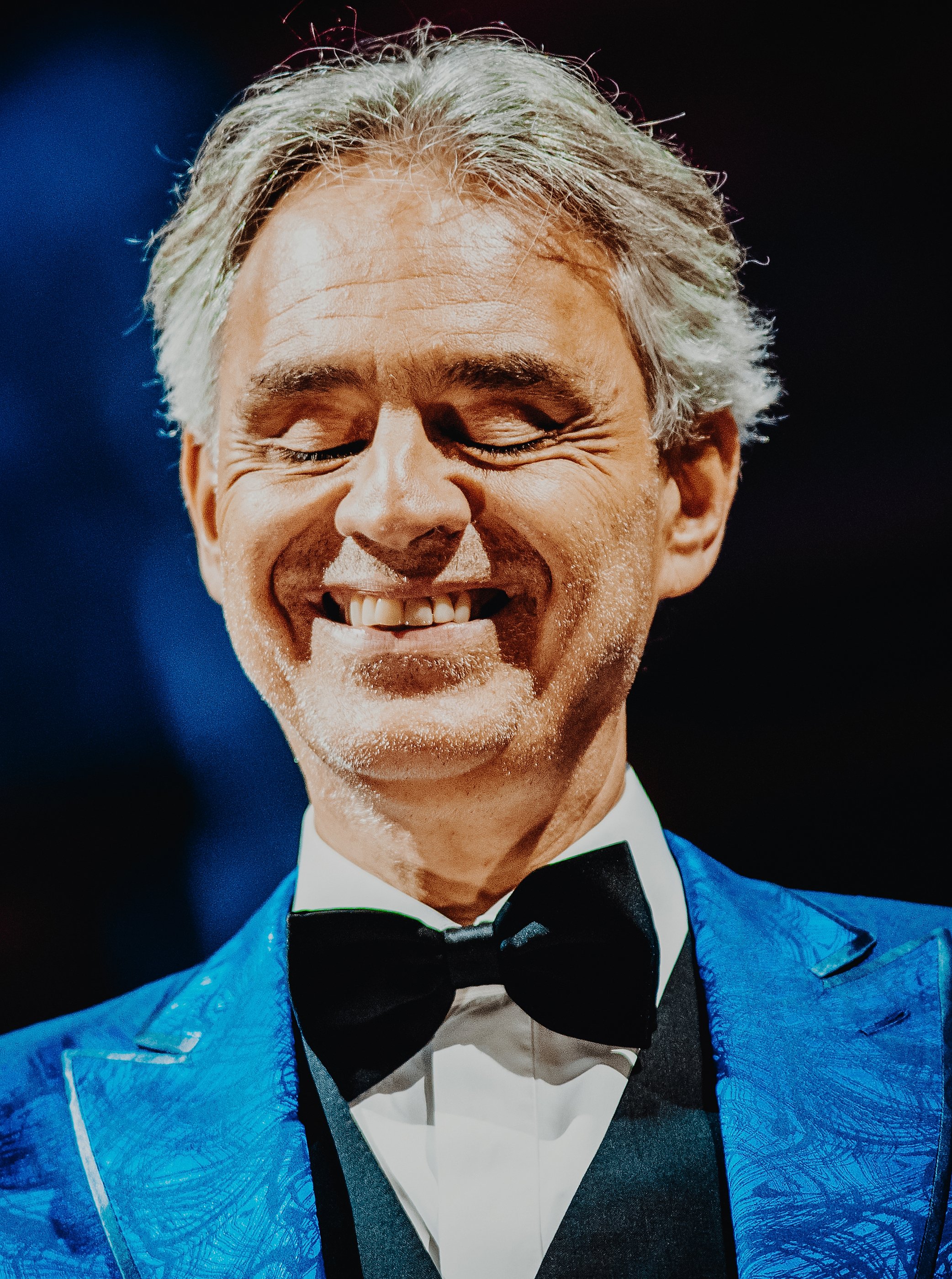 Andrea Bocelli smiling in a blue jacket