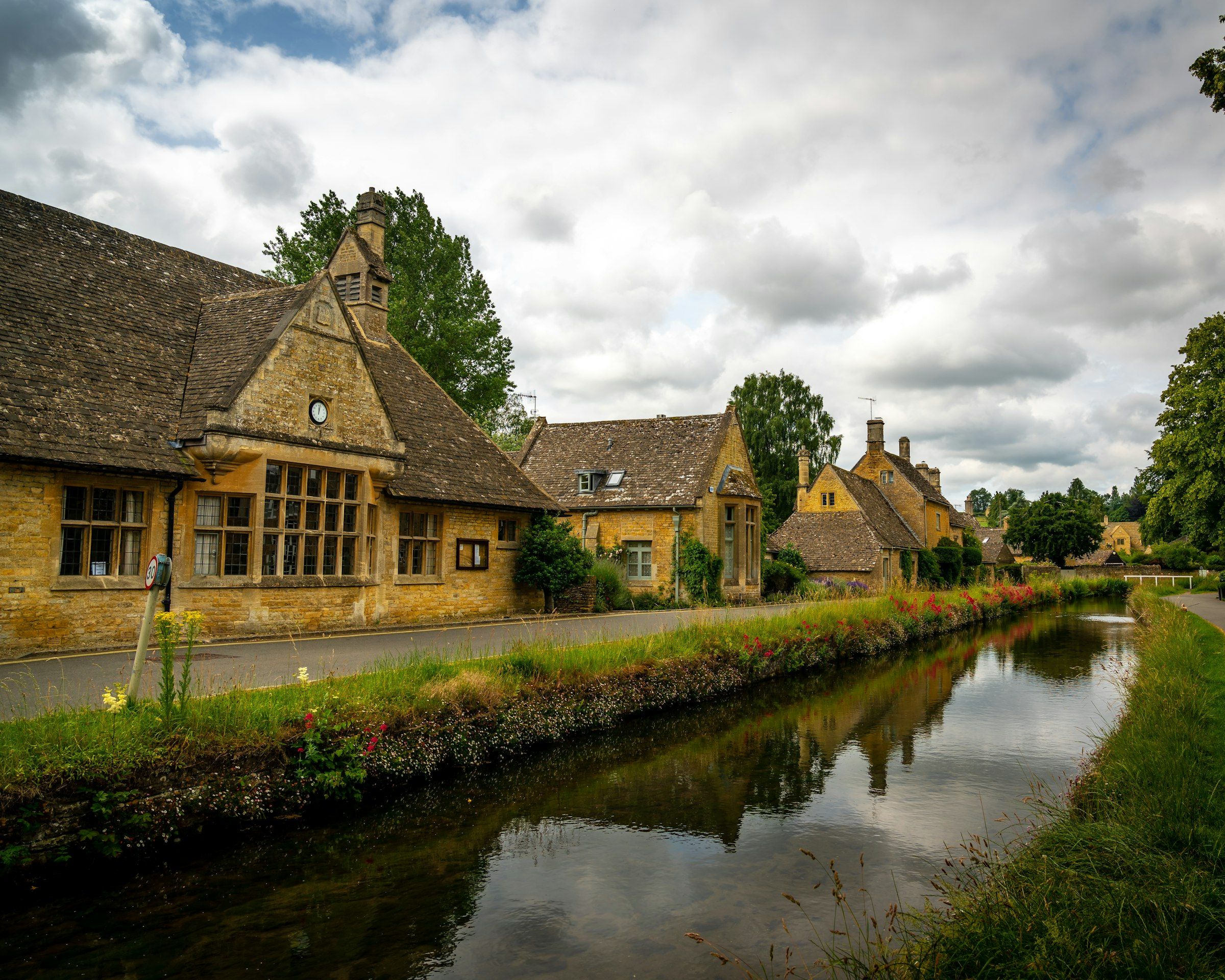 Cheltenham and the Cotswolds (brown and gray house beside river under cloudy sky during daytime)