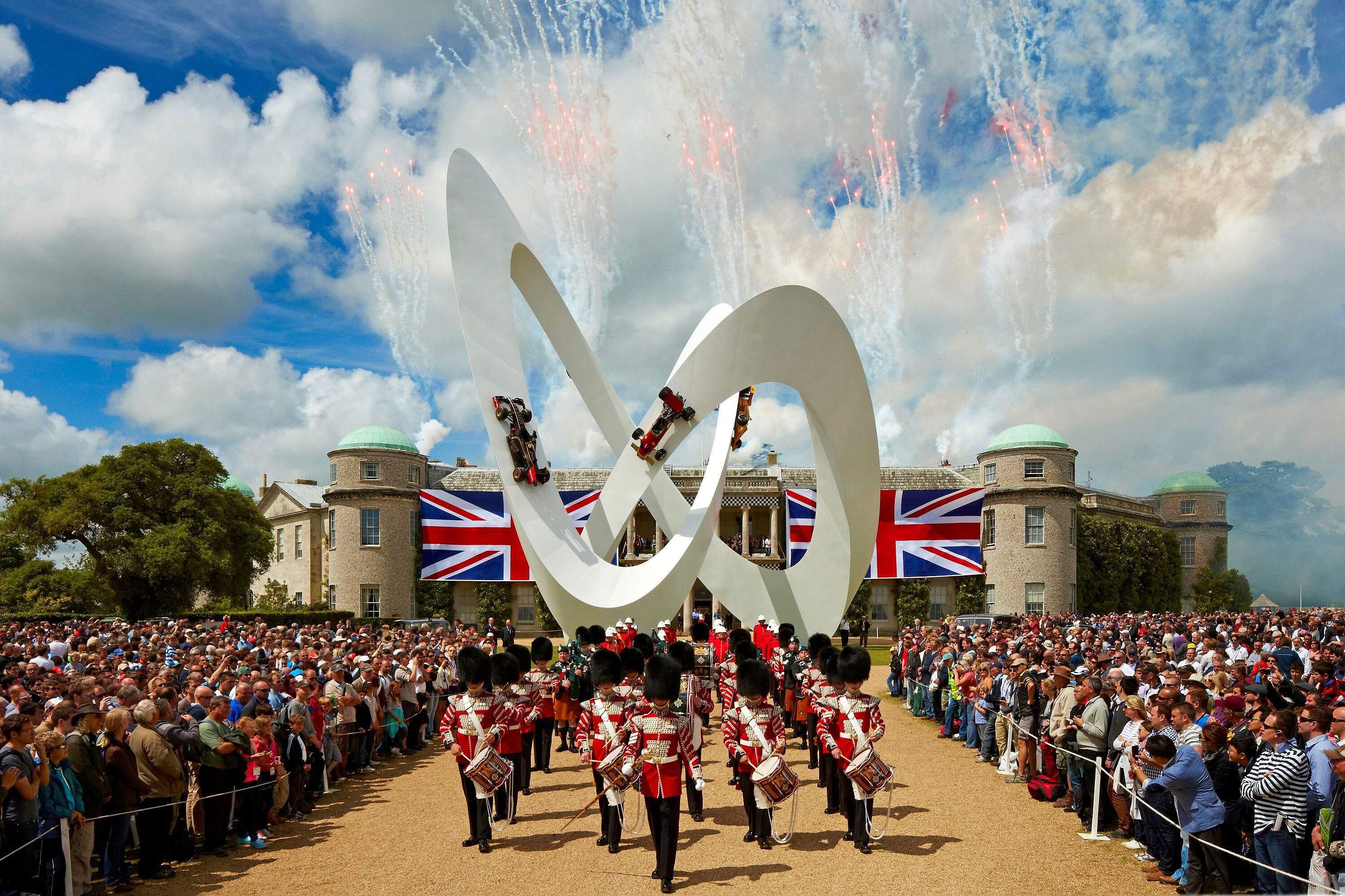 Fireworks over the Central Feature sculpture and a marching band in front of Goodwood House
