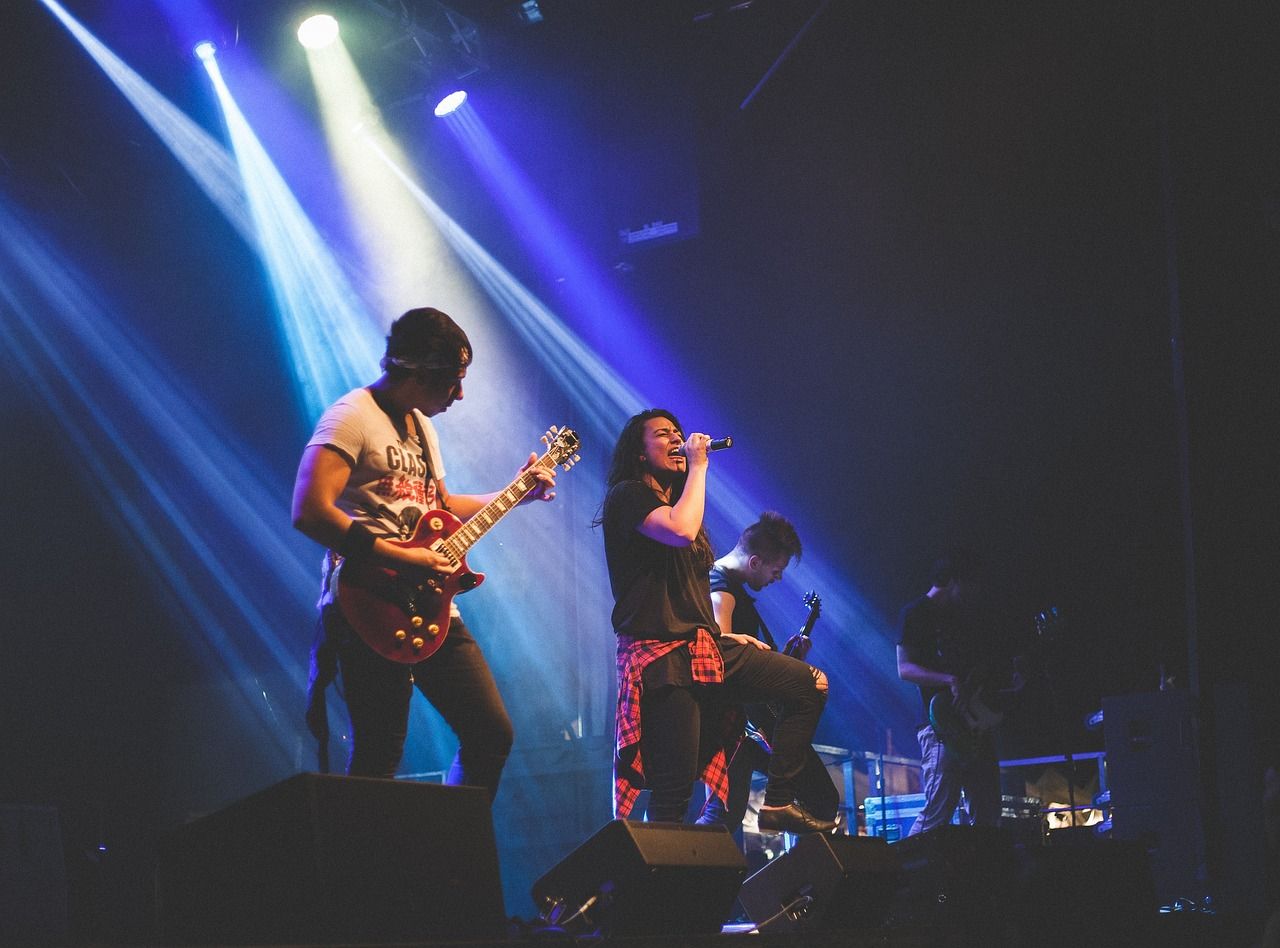 Singer and guitarist performing under concert spotlight