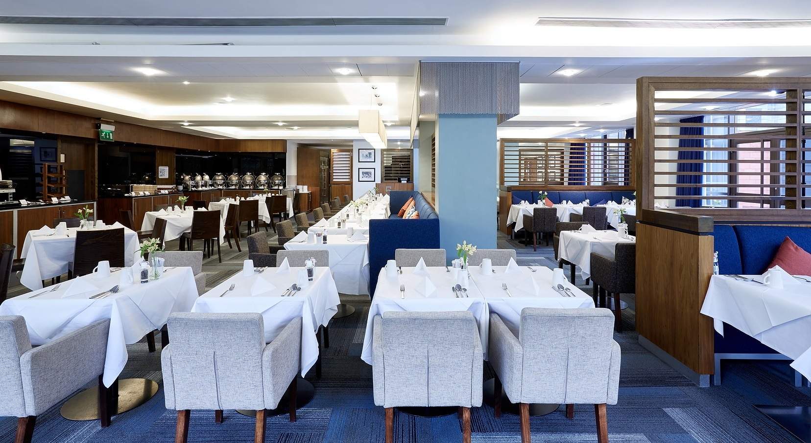Tables laid with white linen and grey chairs in the Blues Dining restaurant at Stamford Bridge