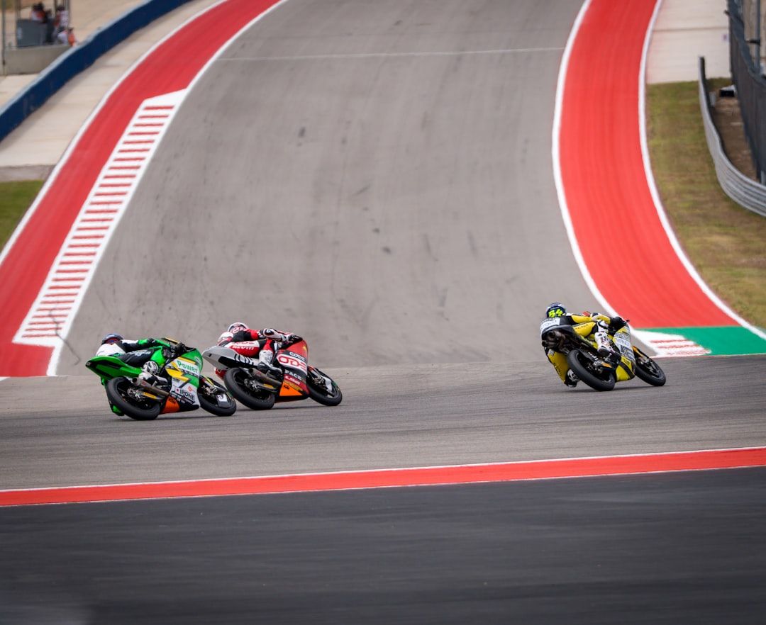Motorcycles racing on a circuit with red and white kerbs