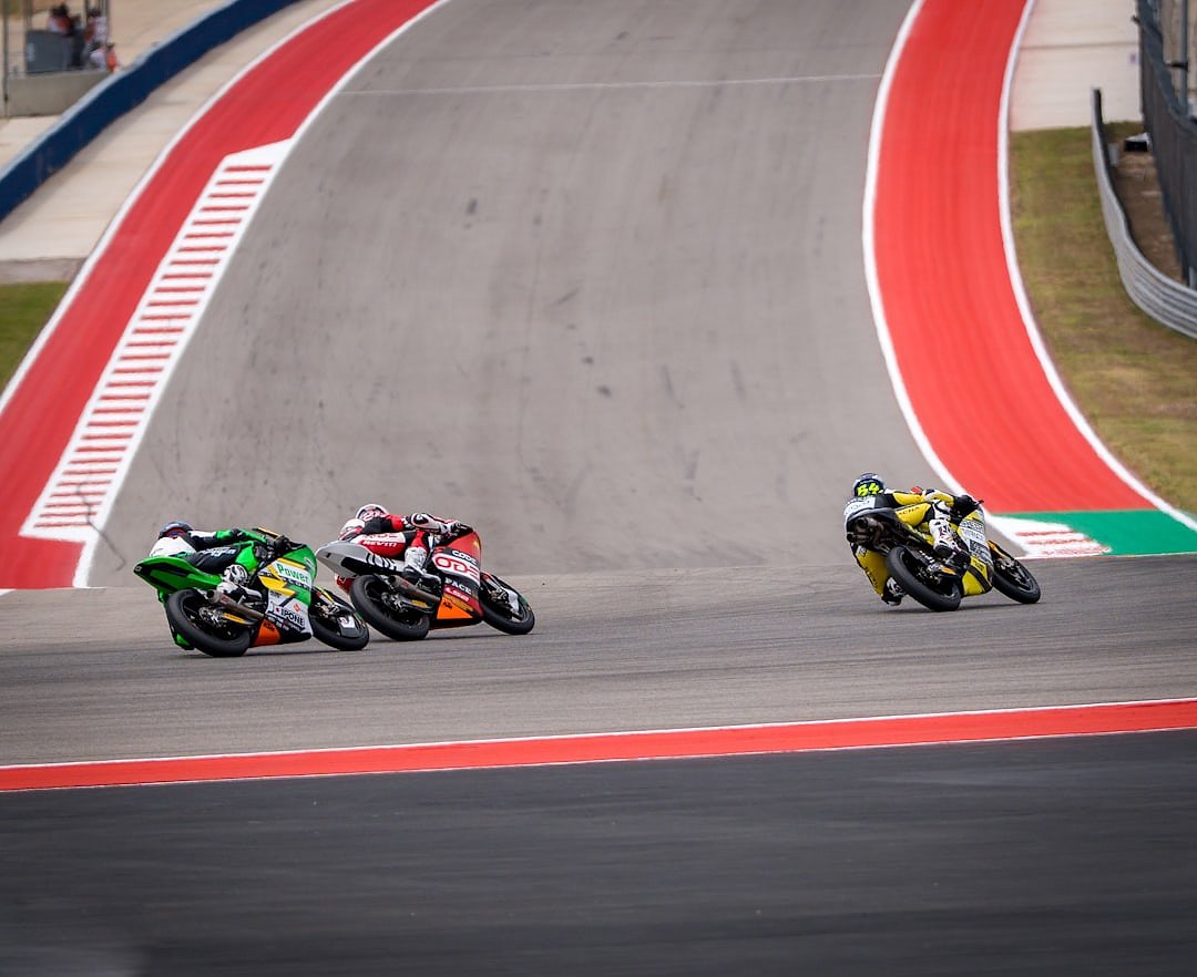 Motorcycles racing on a circuit with red and white kerbs