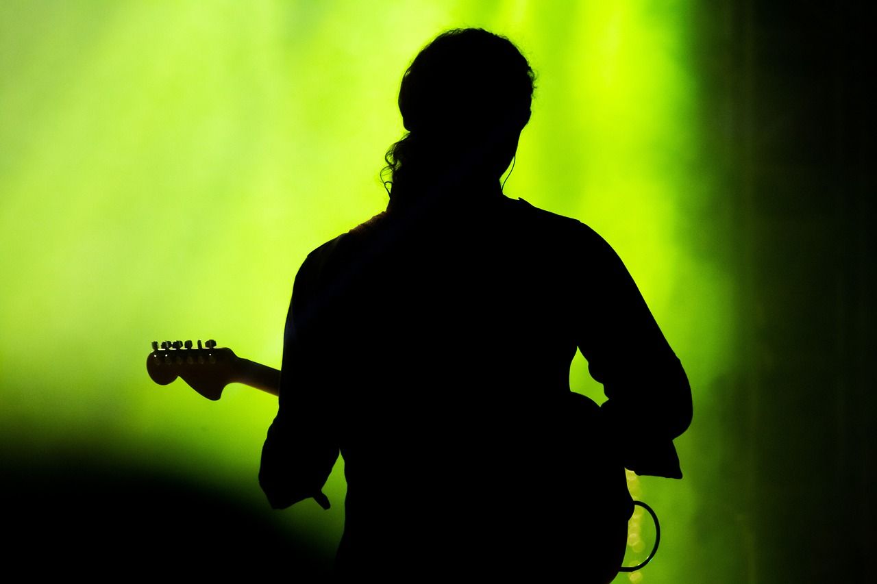 Guitarist silhouetted against stage smoke and lights during a live performance