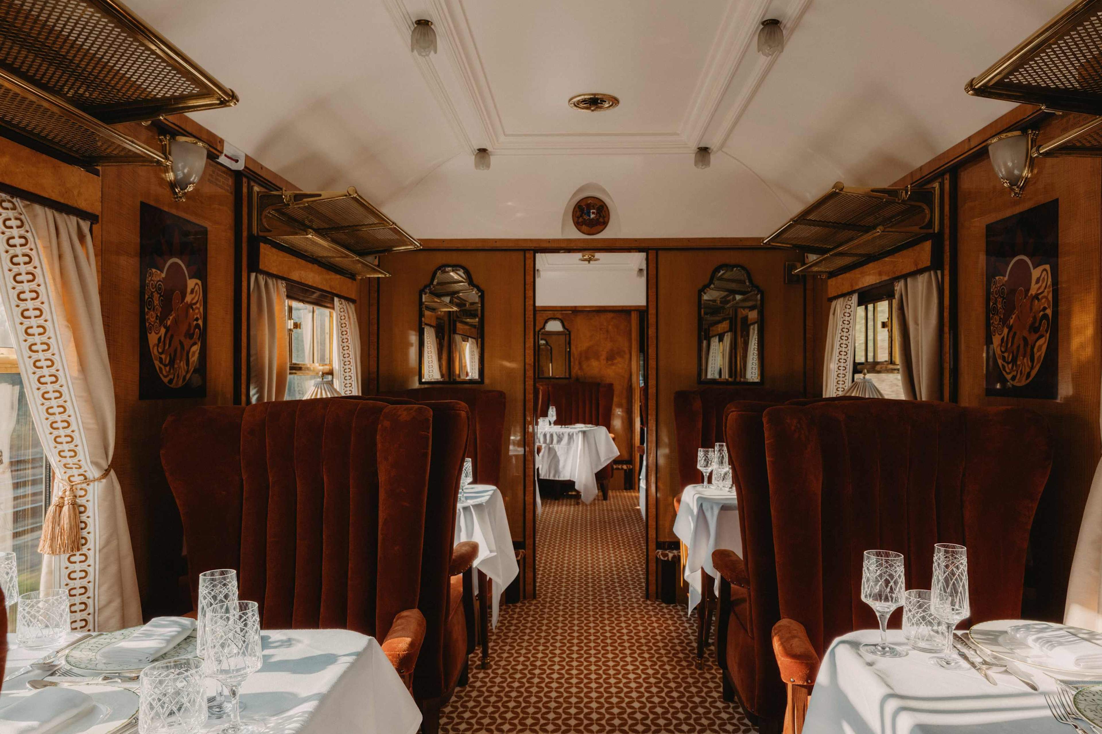 Wood-panelled carriage interior with velvet armchairs and laid tables