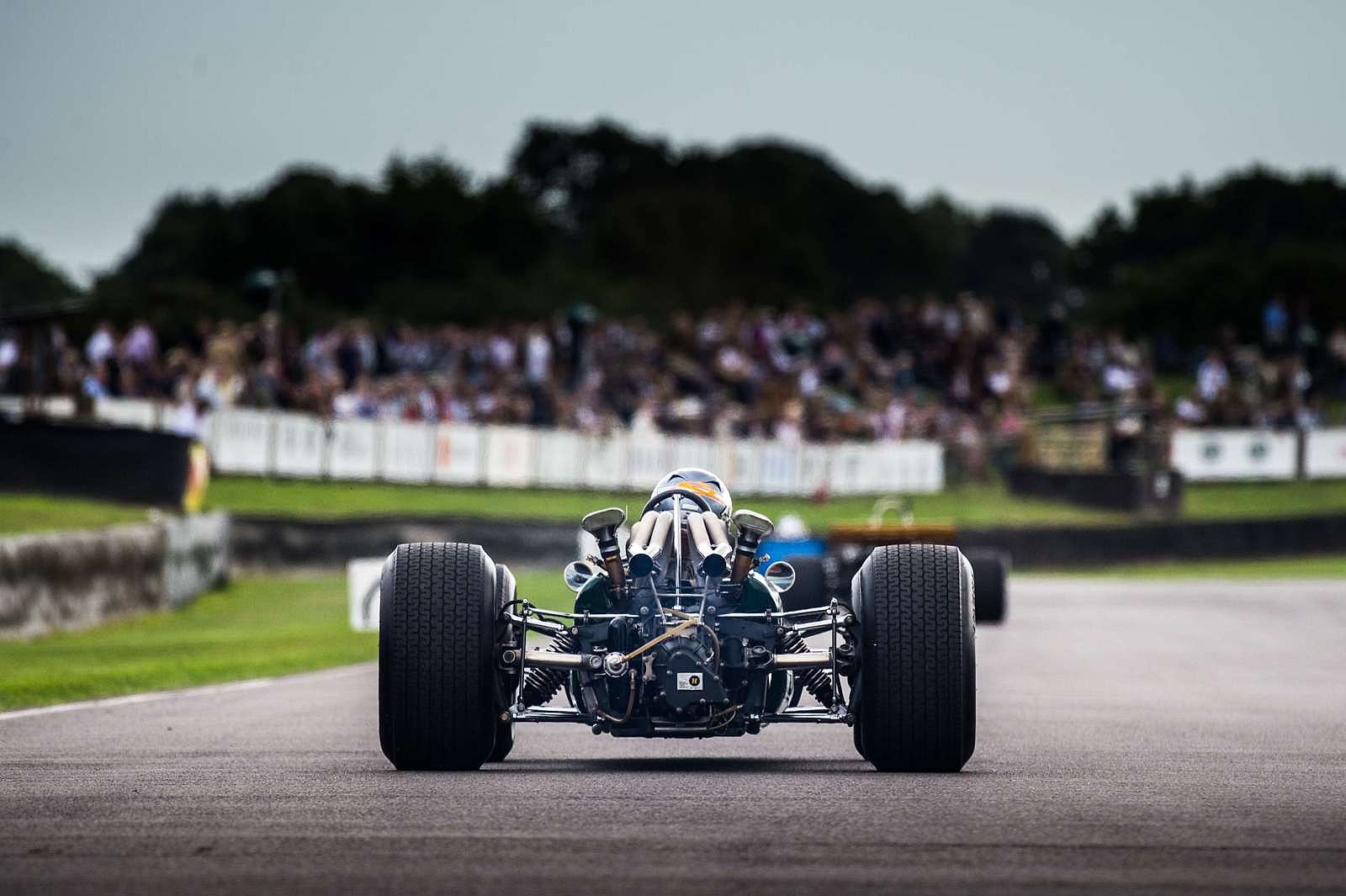 A Brabham Formula 1 car running before the grandstand crowds during the Goodwood Revival's tribute to Sir Jack Brabham