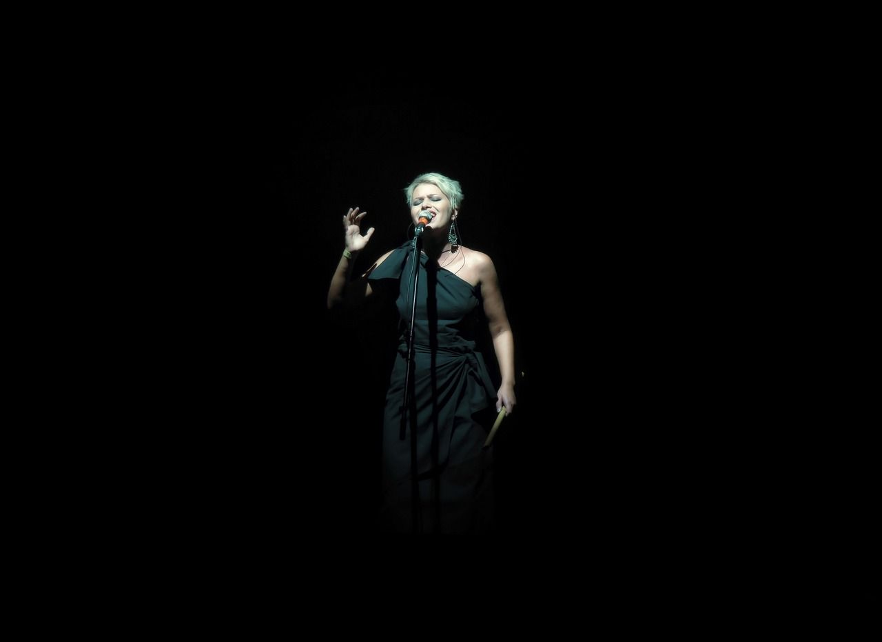 A female singer performing under a spotlight on stage