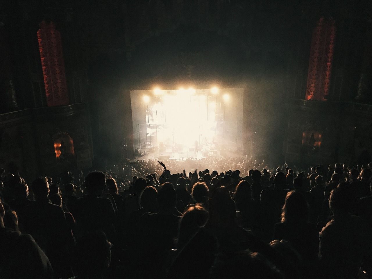 Concert audience silhouetted against dramatic stage spotlights