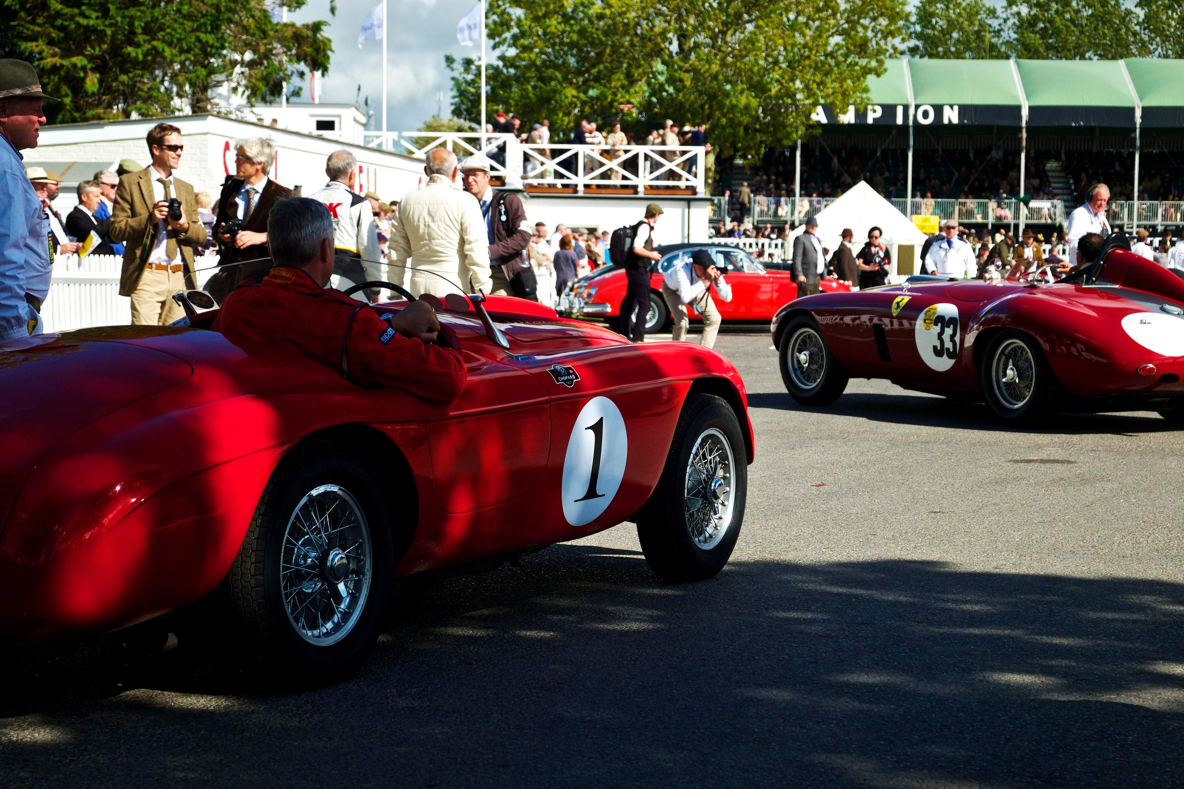 Vintage red Ferraris with period-dress spectators at the Goodwood Revival