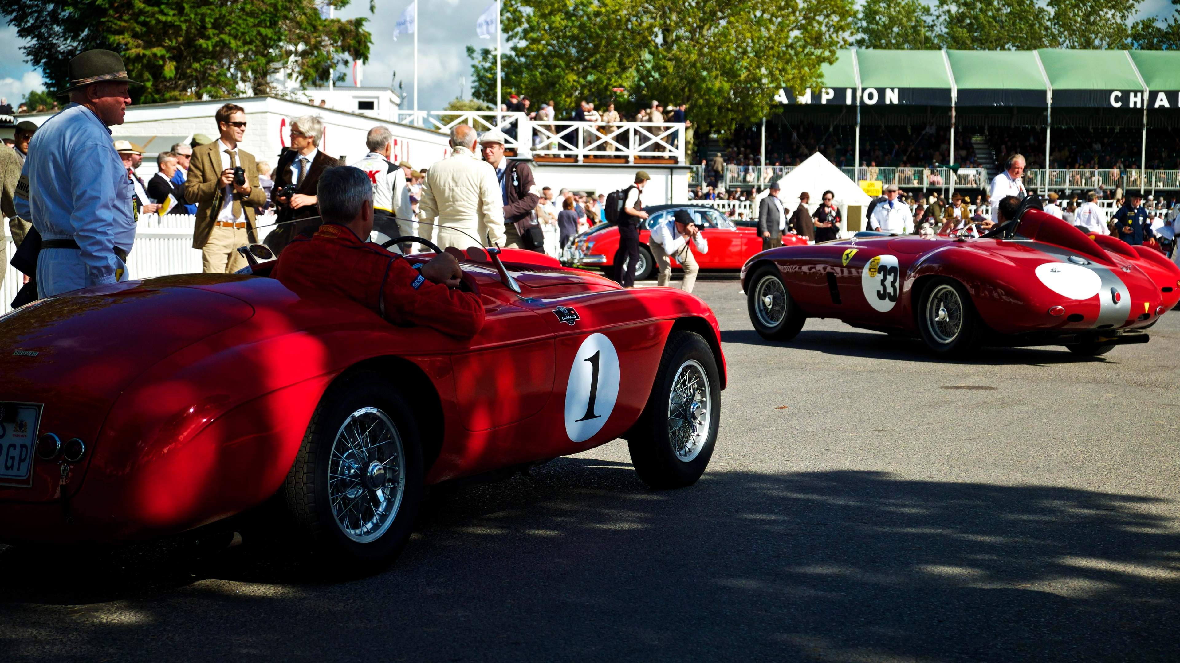 Vintage red Ferraris with period-dress spectators at the Goodwood Revival