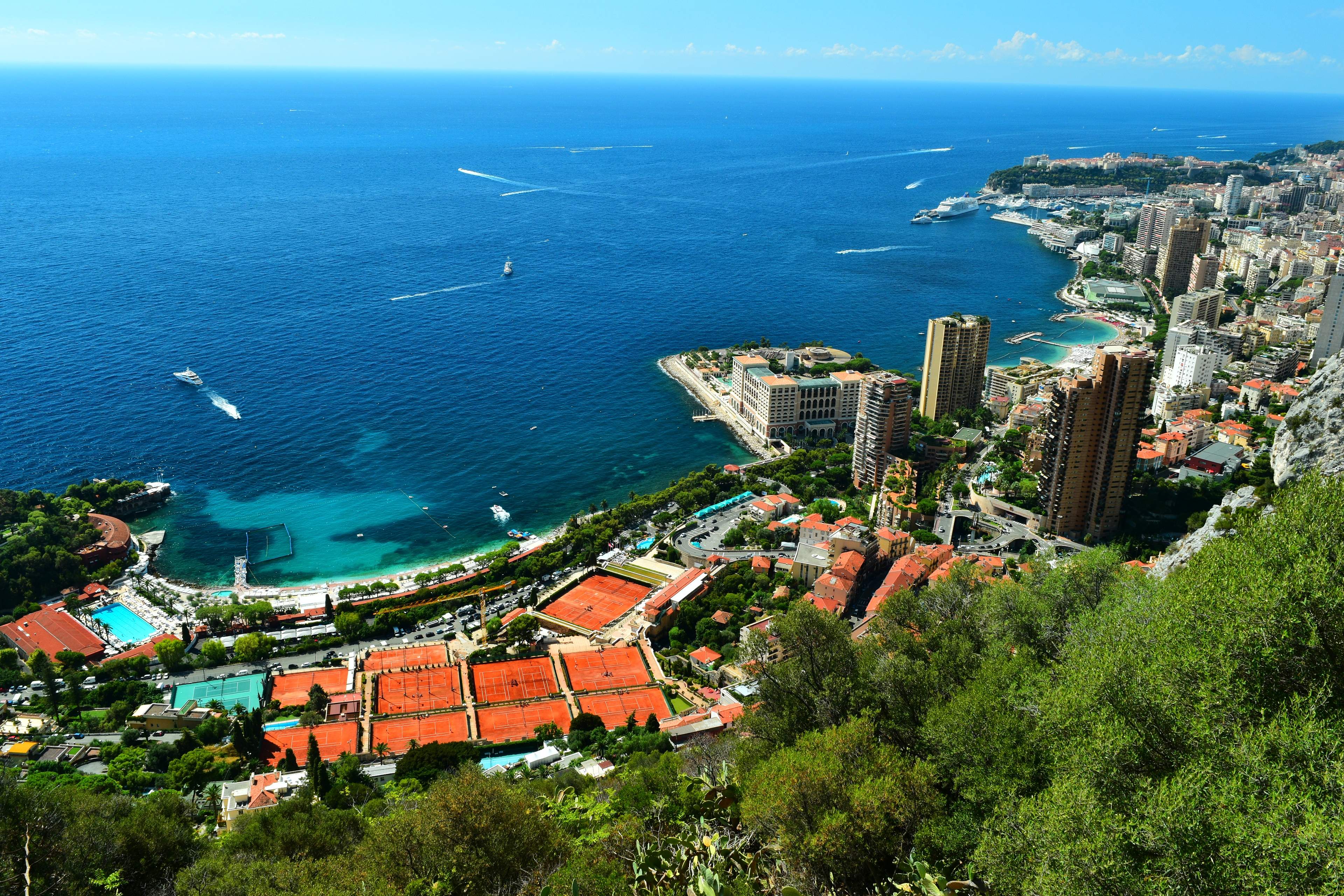 The terraced red clay courts of the Monte-Carlo Country Club above the sea, with Monaco stretching along the coast beyond