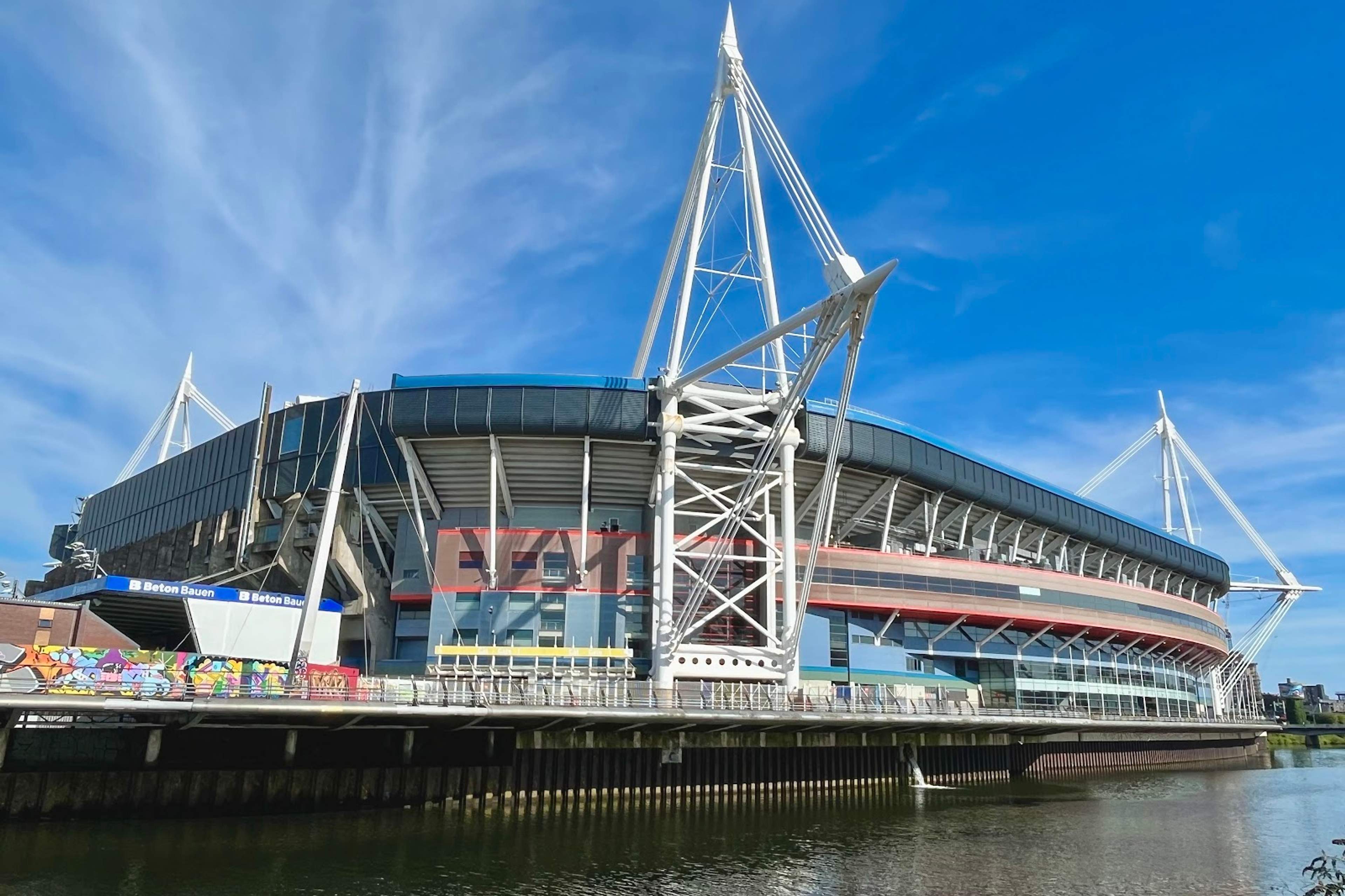 The Principality Stadium seen across the River Taff, its white masts rising against a clear sky