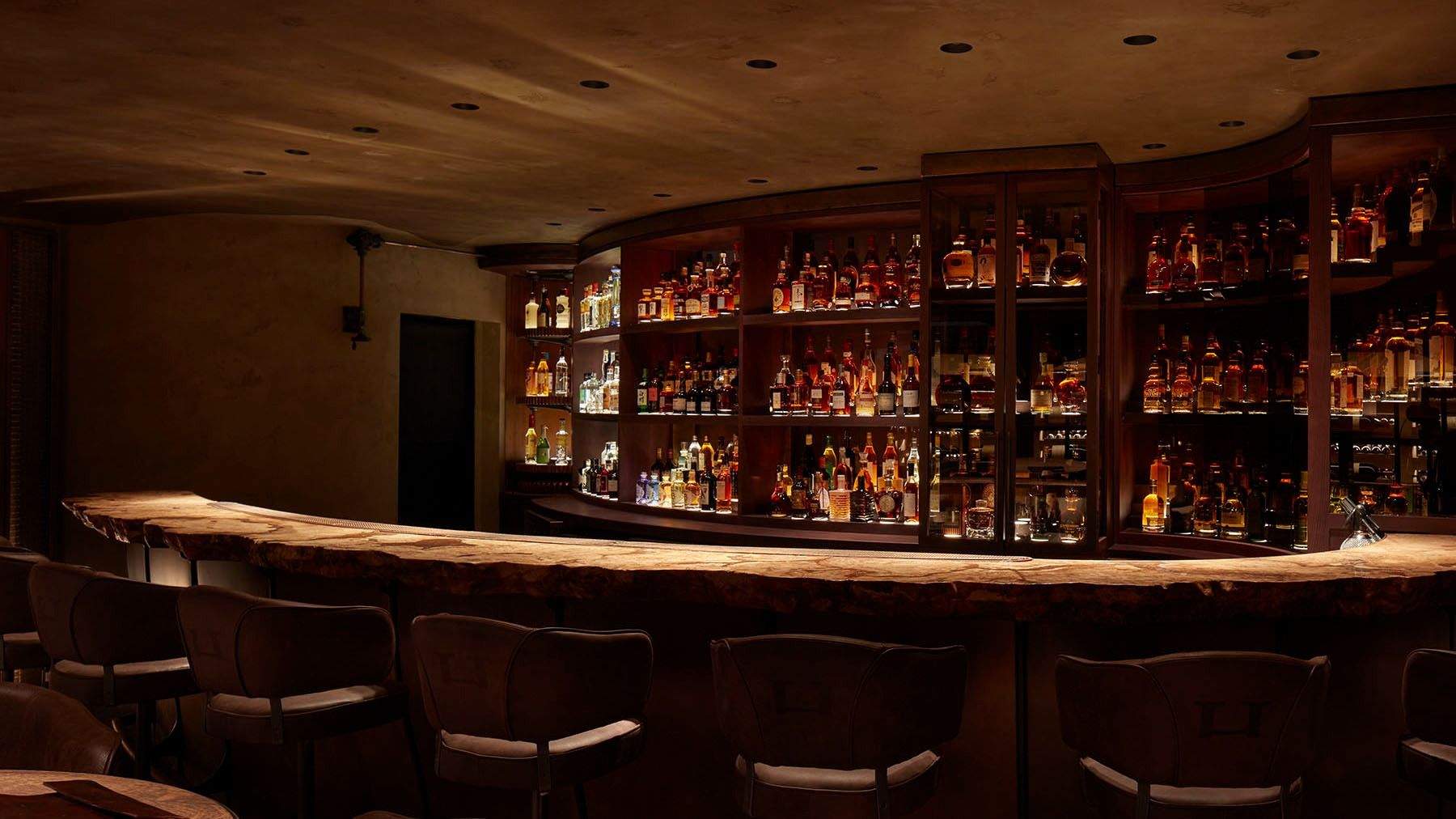 The Bar Below at HIDE, a curved bar lined with bottles under low lights