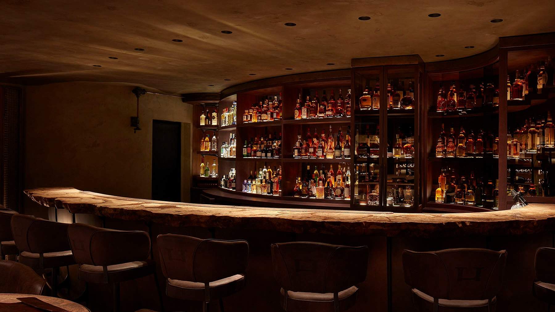 The Bar Below at HIDE, a curved bar lined with bottles under low lights