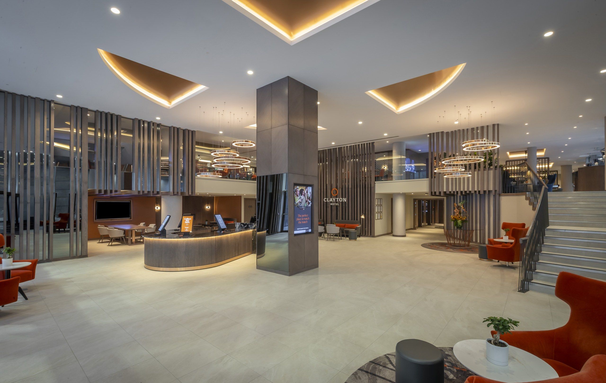 The reception desk in the lobby, with orange armchairs and a staircase to one side