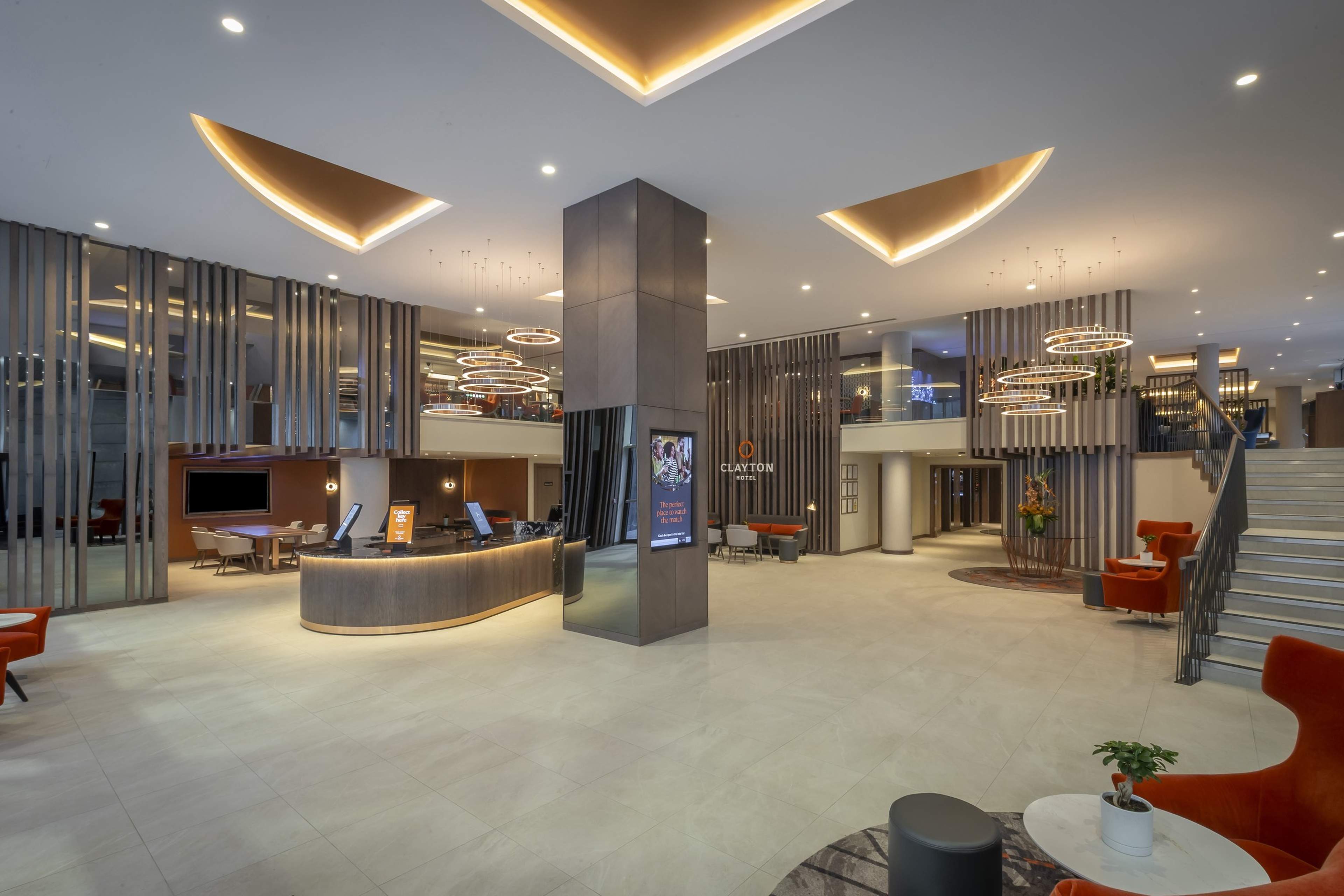 The reception desk in the lobby, with orange armchairs and a staircase to one side