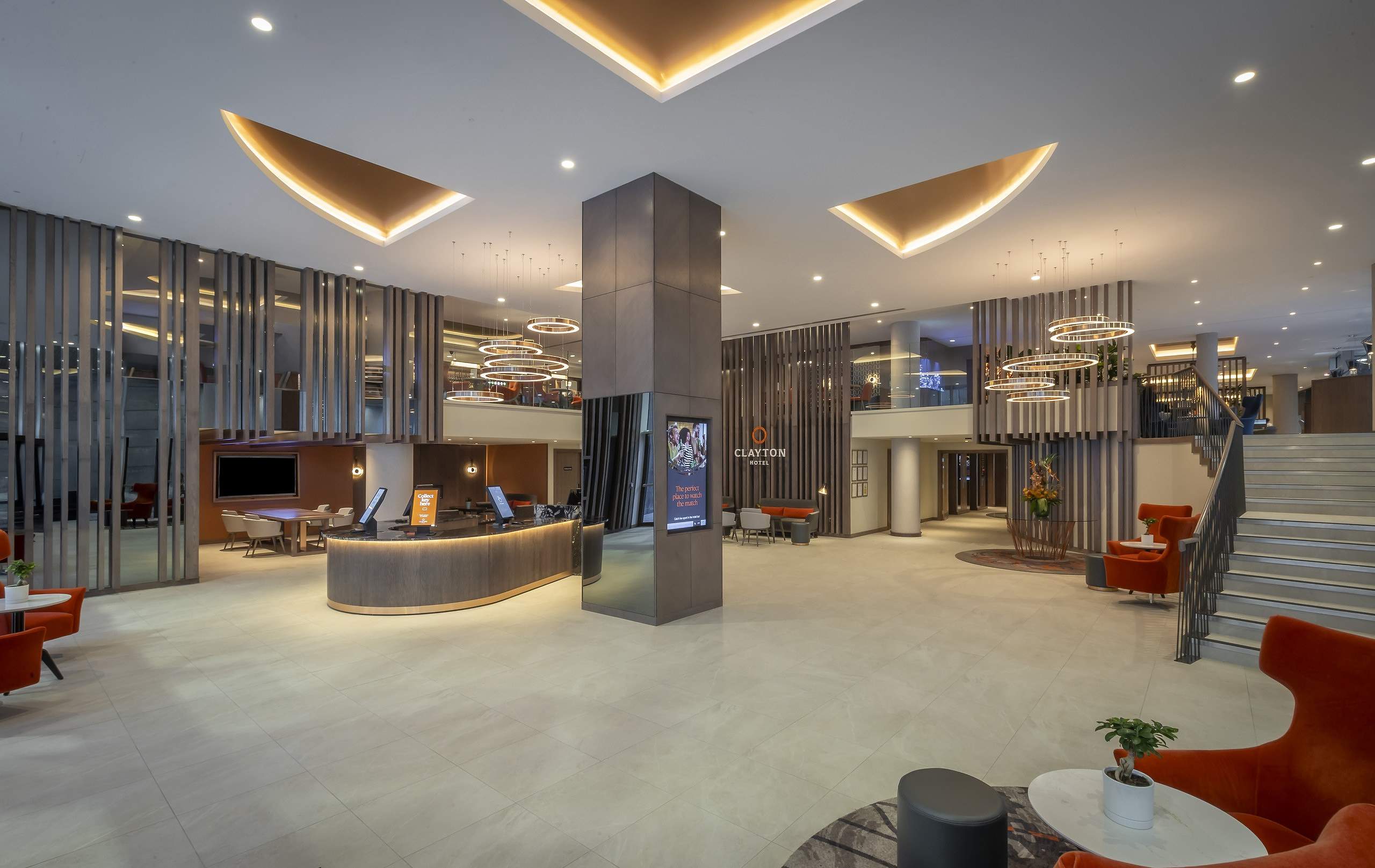 The reception desk in the lobby, with orange armchairs and a staircase to one side