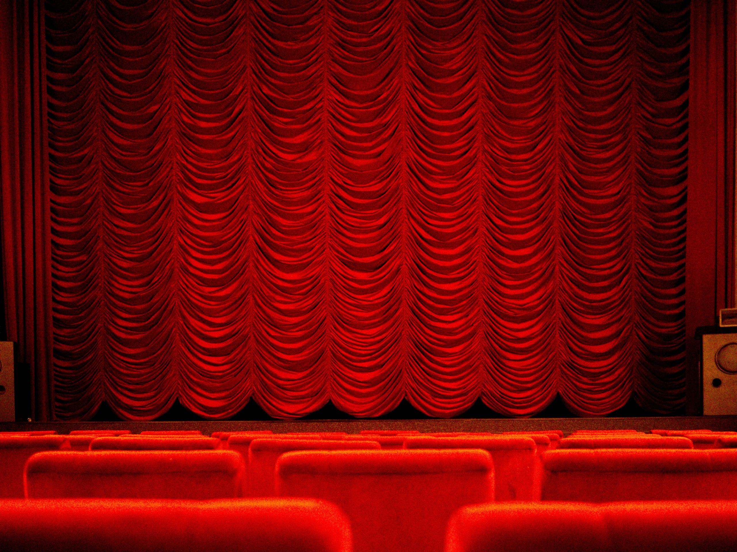 Red house curtain above rows of red theatre seats