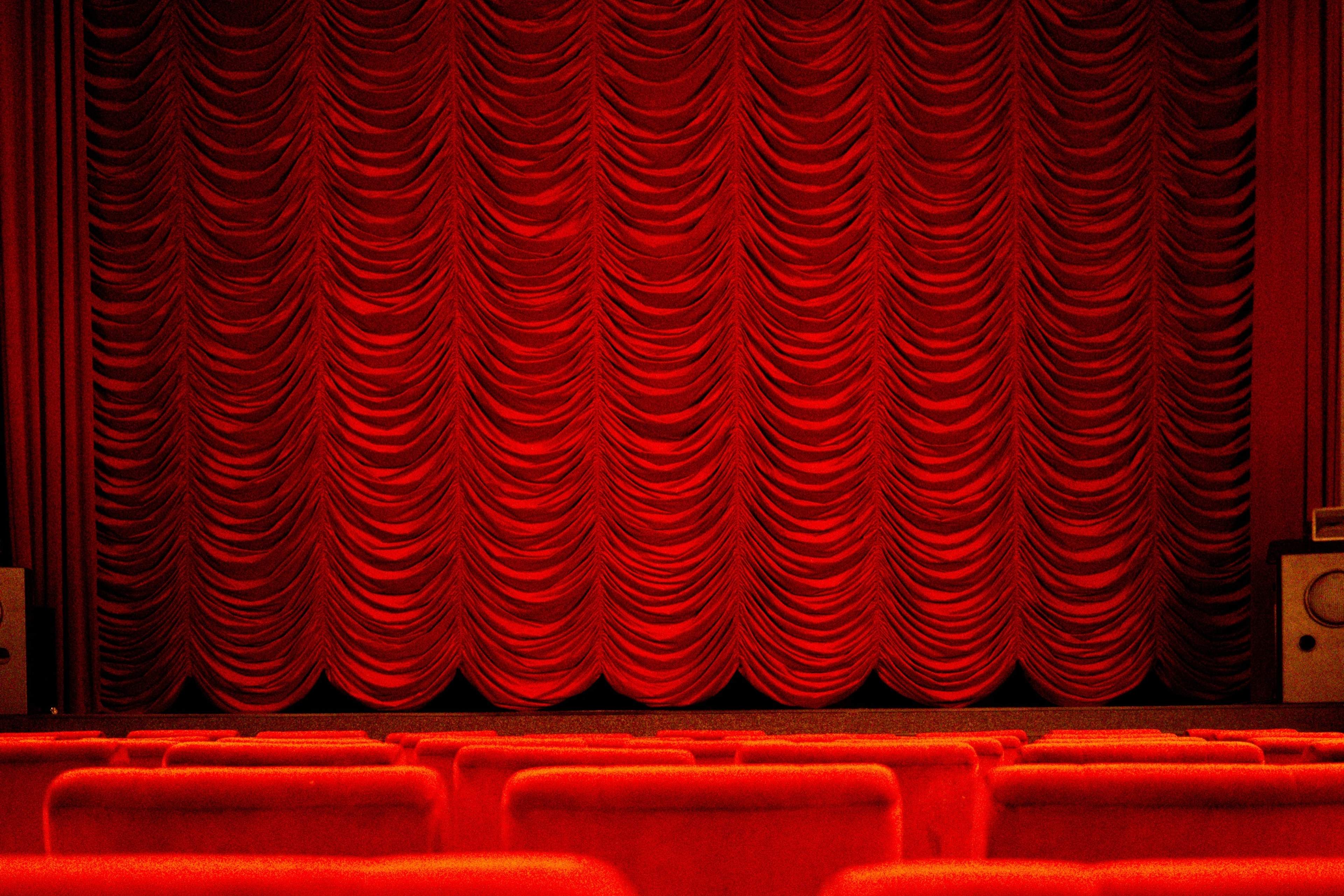 Red house curtain above rows of red theatre seats