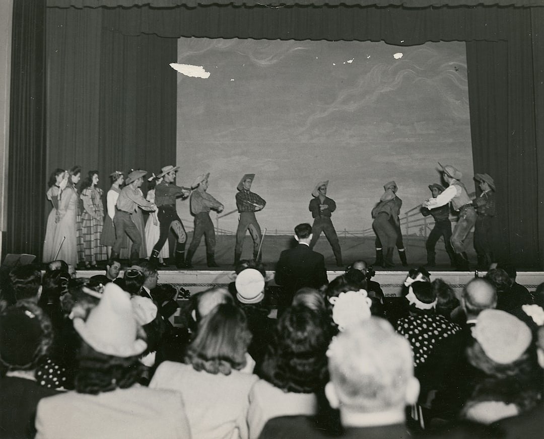 Vintage black and white photograph of performers on a theatre stage in the early 20th century