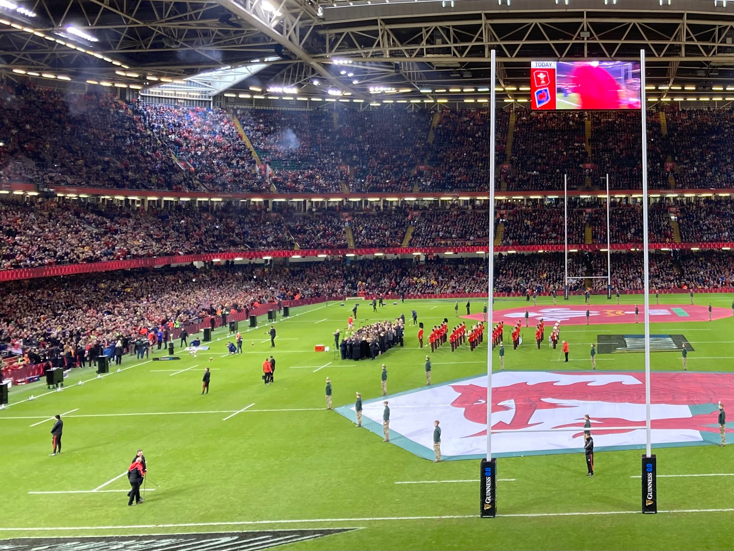 The Principality Stadium in Cardiff before a Six Nations match, with the roof closed, a giant Welsh flag laid across the pitch and the choirs lined up in front of it
