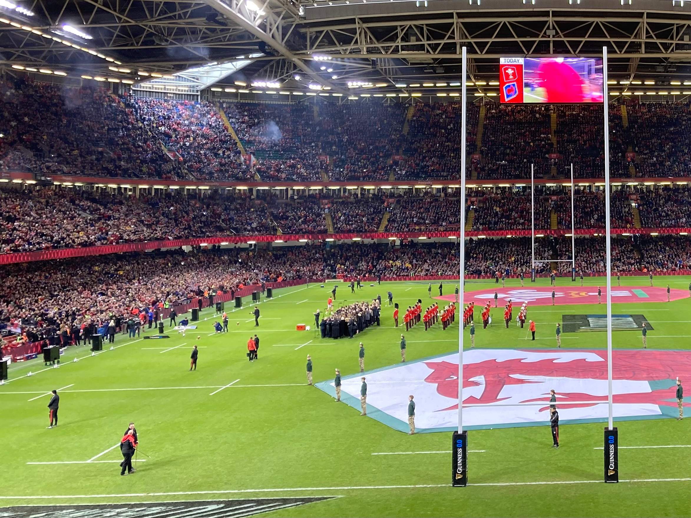 The Principality Stadium in Cardiff before a Six Nations match, with the roof closed, a giant Welsh flag laid across the pitch and the choirs lined up in front of it