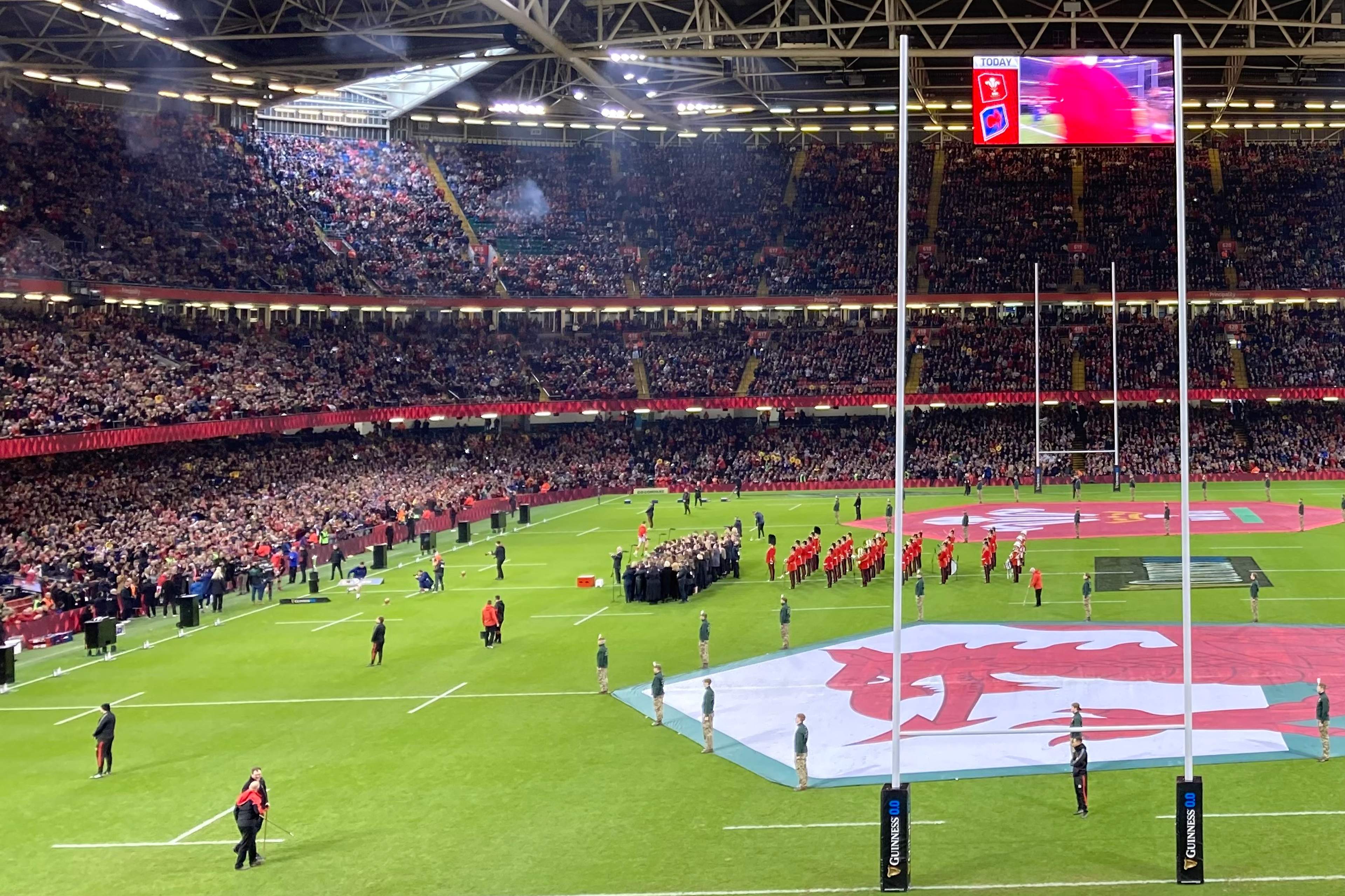 The Principality Stadium in Cardiff before a Six Nations match, with the roof closed, a giant Welsh flag laid across the pitch and the choirs lined up in front of it