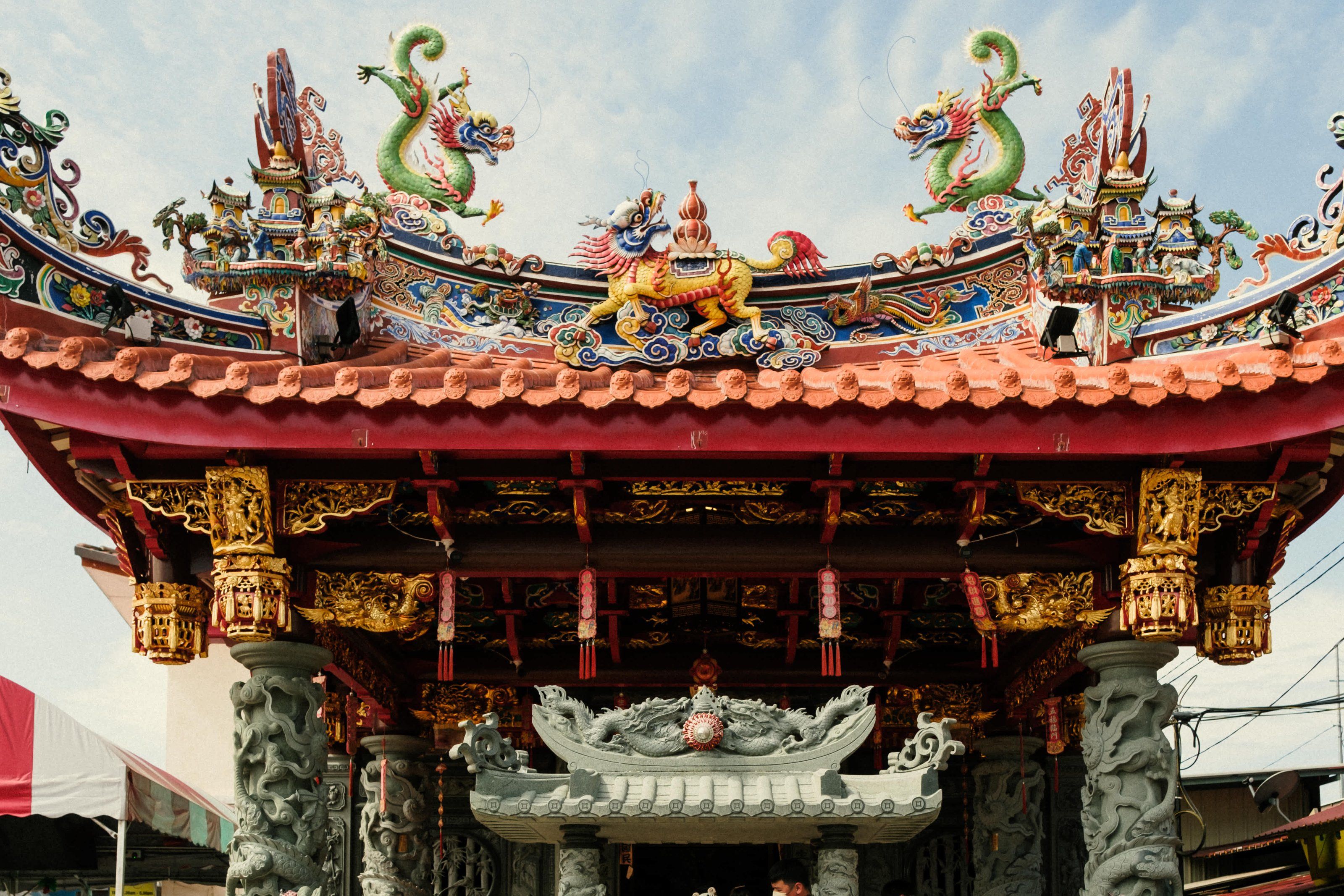 Green and yellow dragons on the red roof of the temple at the entrance to Chew Jetty in George Town, Penang.