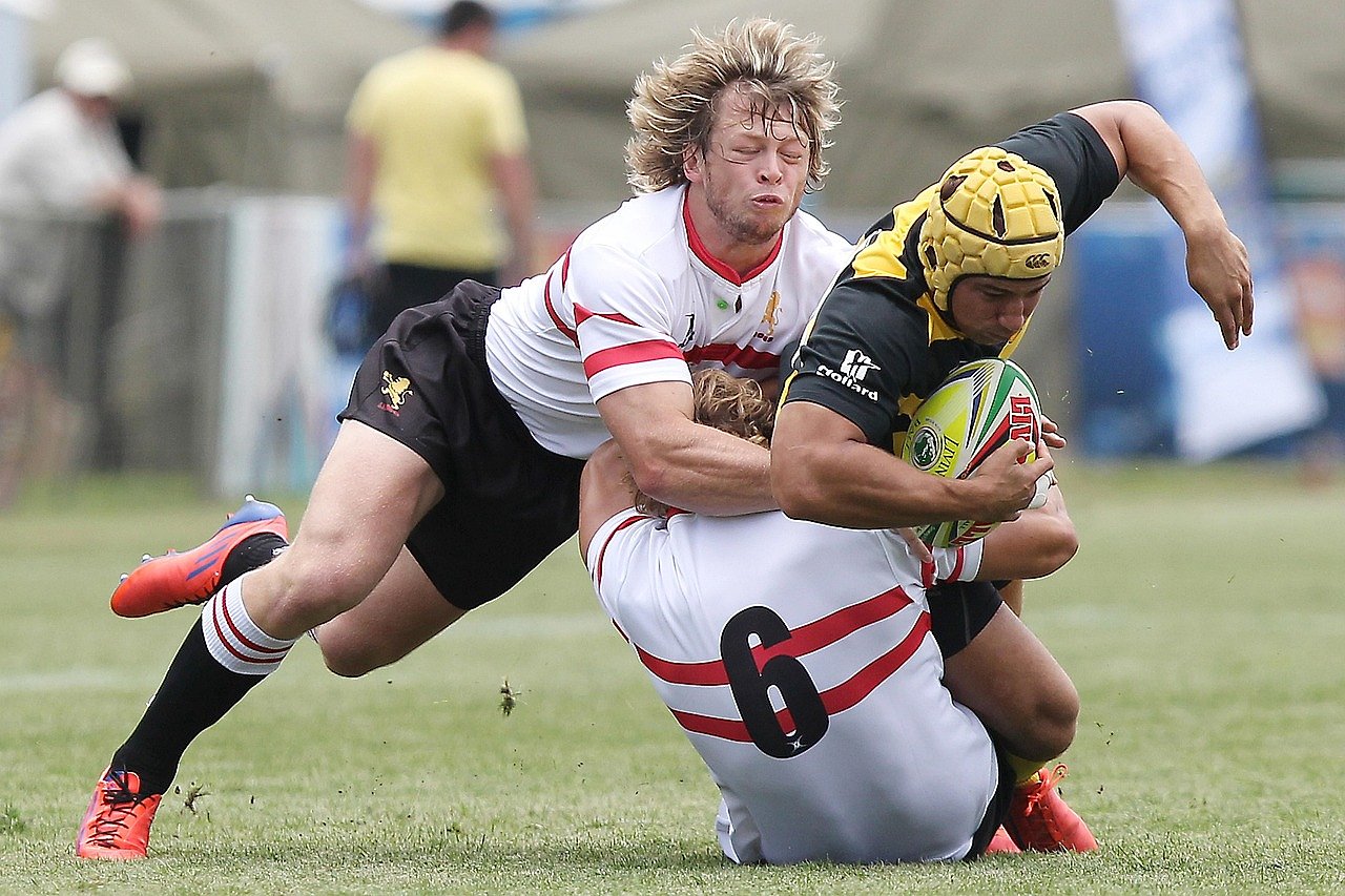 Rugby players competing in a tackle during a match