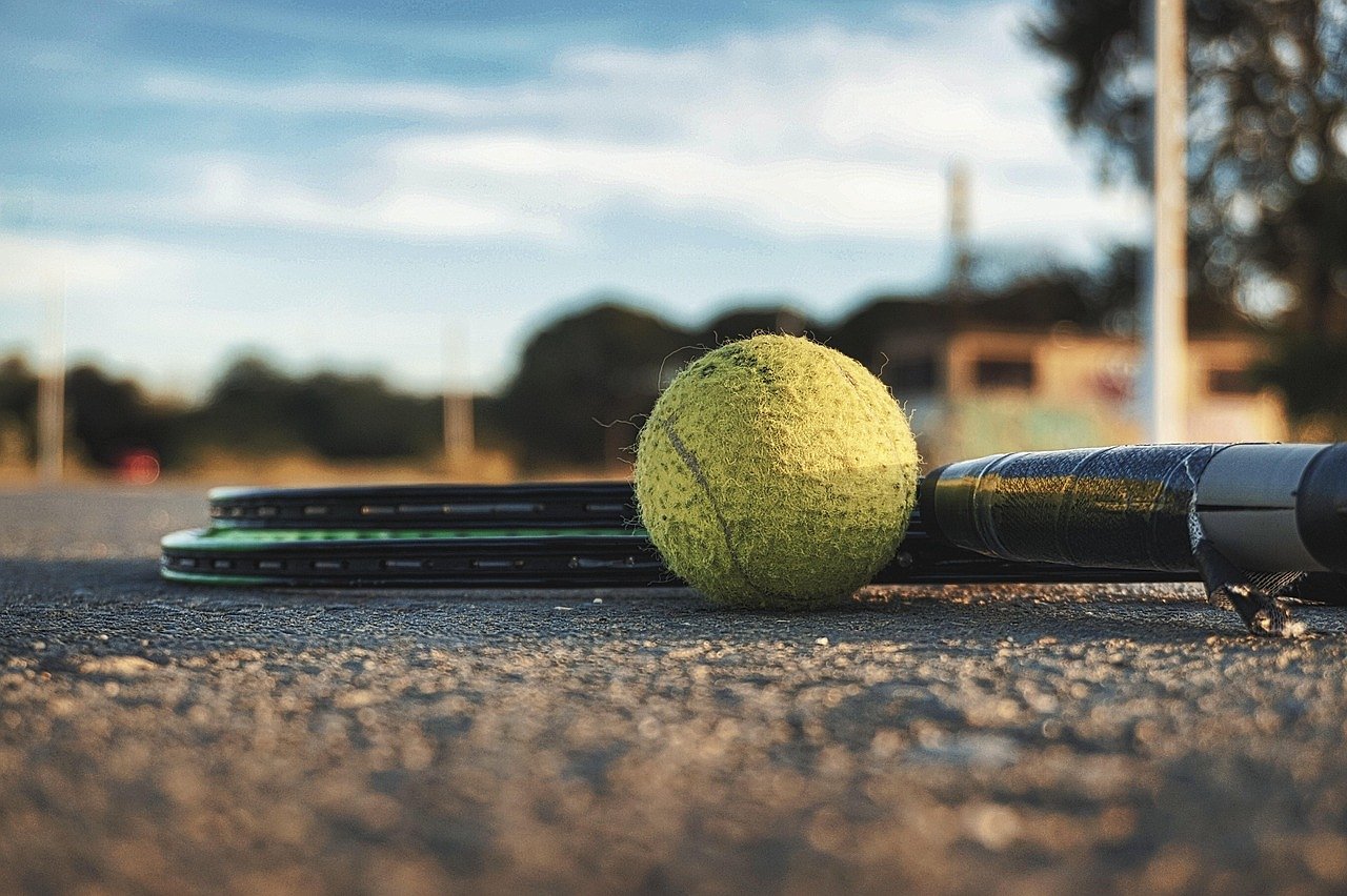 Tennis ball and racket on court, evoking the competitive intensity of the McEnroe era