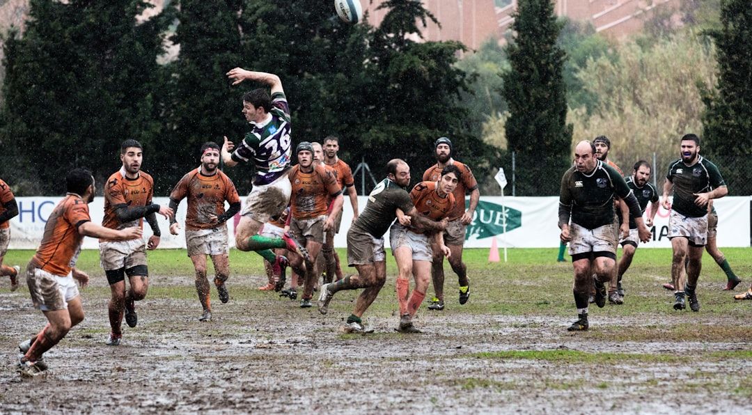 Rugby union match action with a player leaping over defenders
