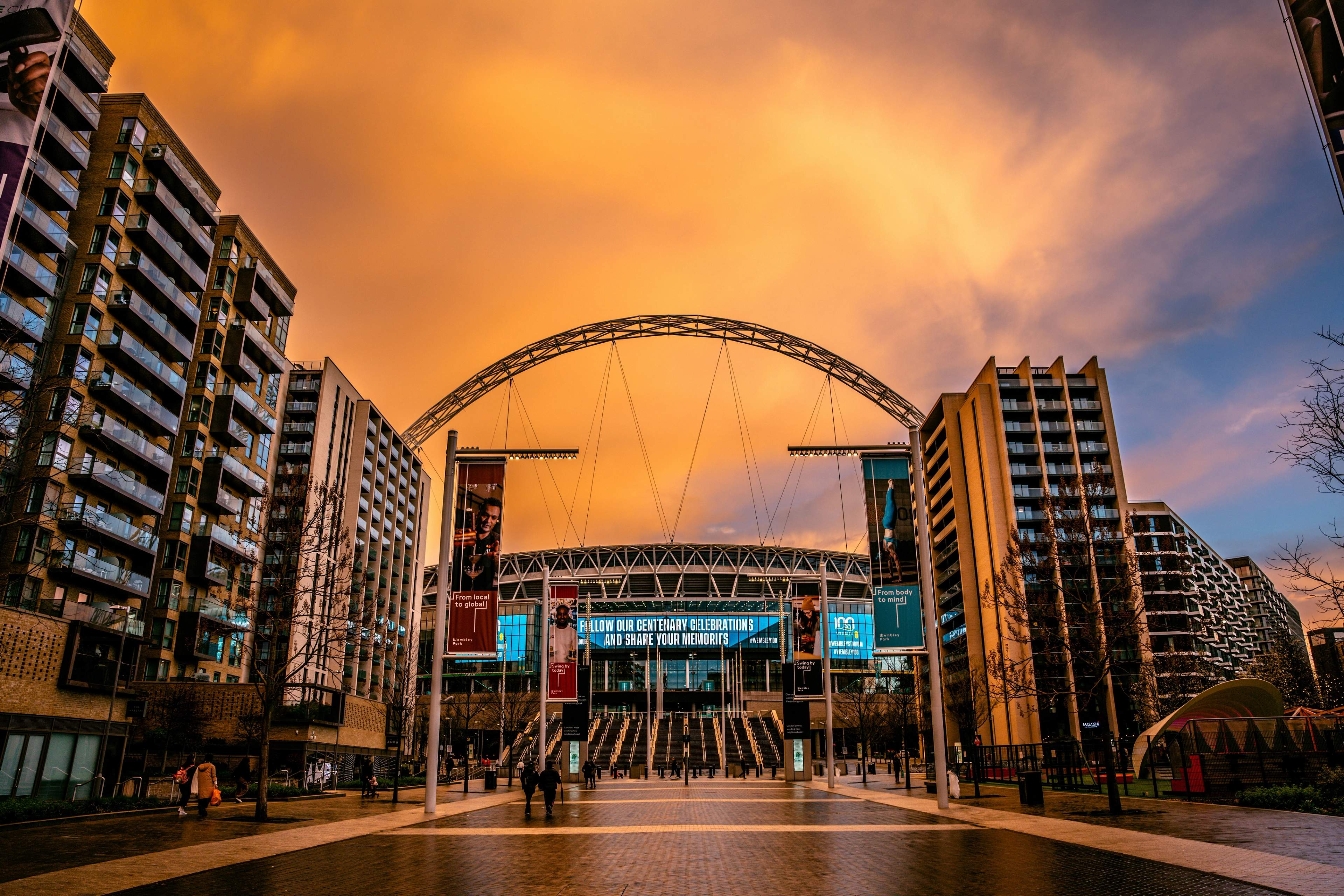 Wembley Stadium and its arch under an orange sunset sky