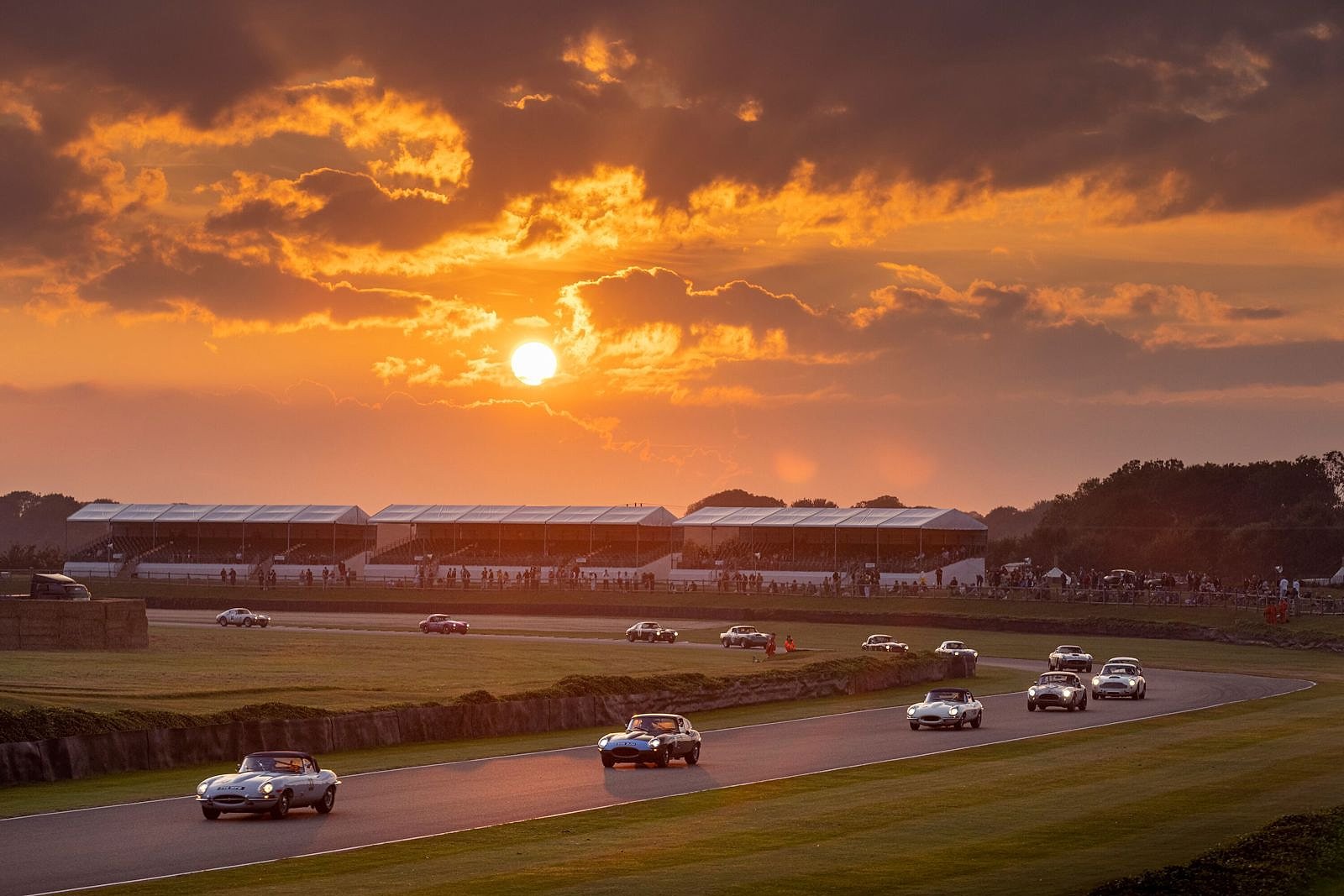 Sports cars racing into the sunset at the Goodwood Revival
